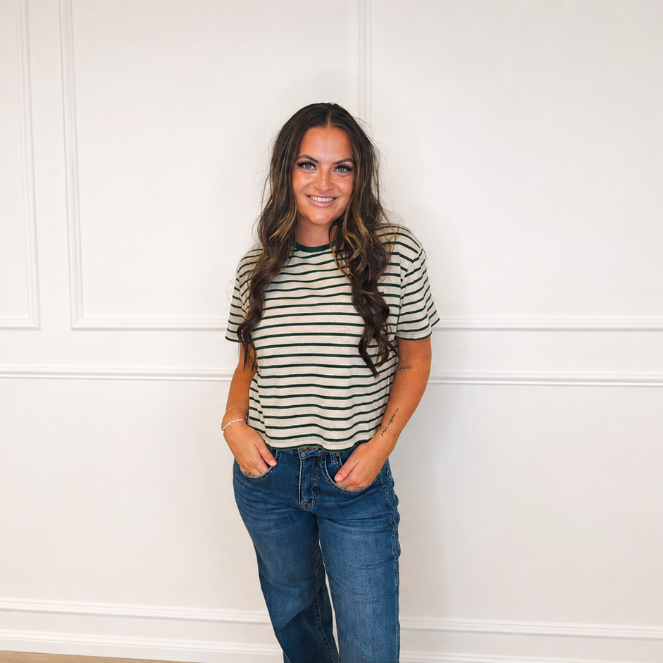 Woman wearing a cream and forest green striped knit tee with medium-wash denim in a bright white studio