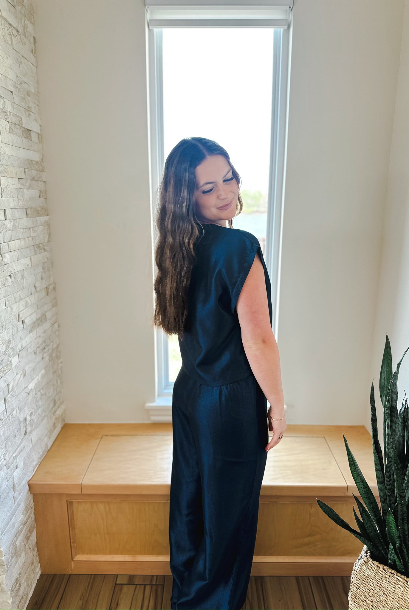 Woman wearing a navy blue shimmer short sleeve top and matching wide-leg pants. Back view.