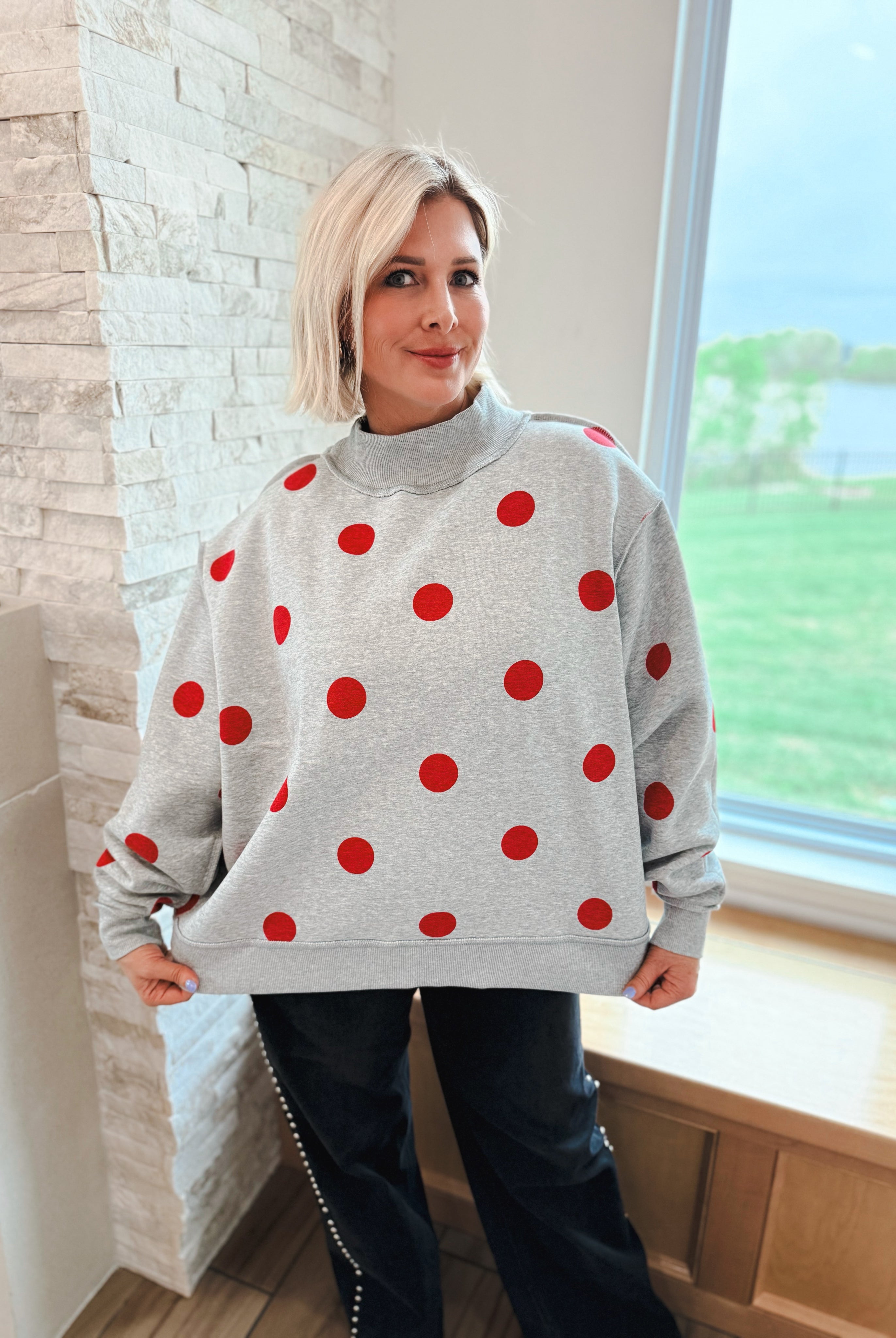 Grey oversized sweatshirt with red polka dots and a mockneck collar.