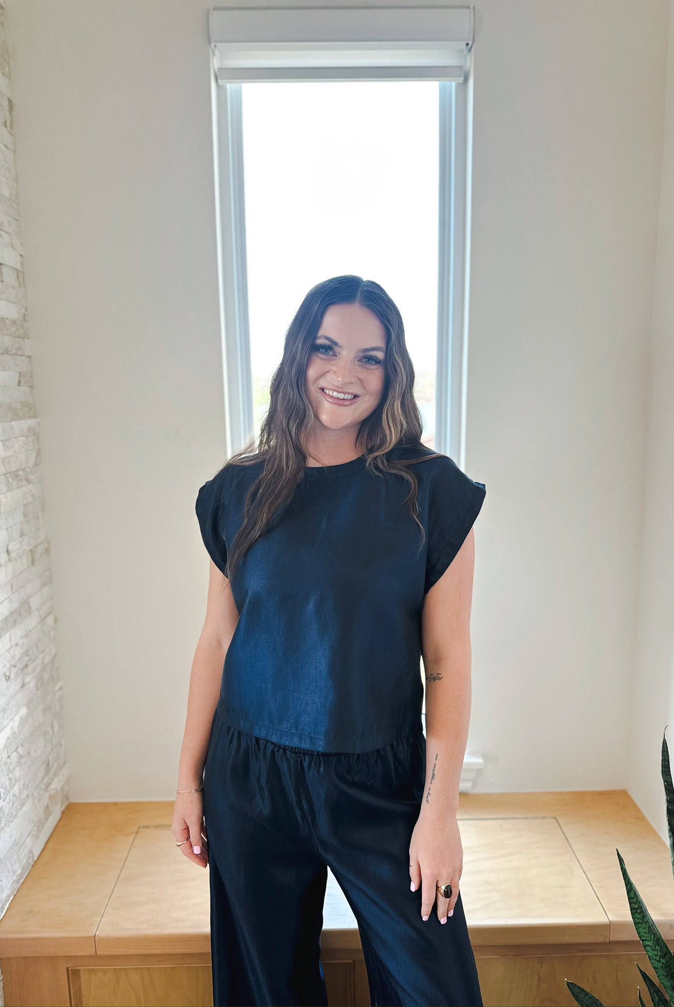 Woman wearing a navy shimmer short sleeve top and matching wide-leg pants, part of an elevated matching set.
