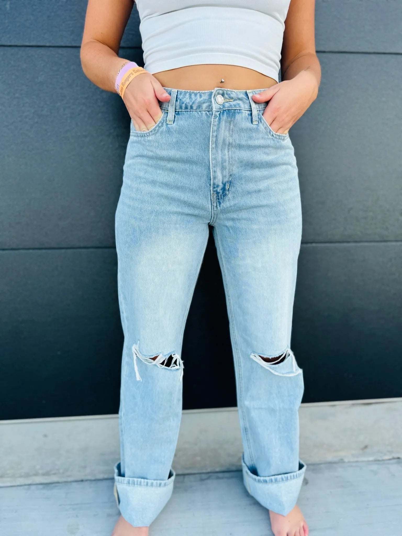 Vintage high rise light wash flare jeans with ripped knees and cuffed hems. Model wears white crop top.