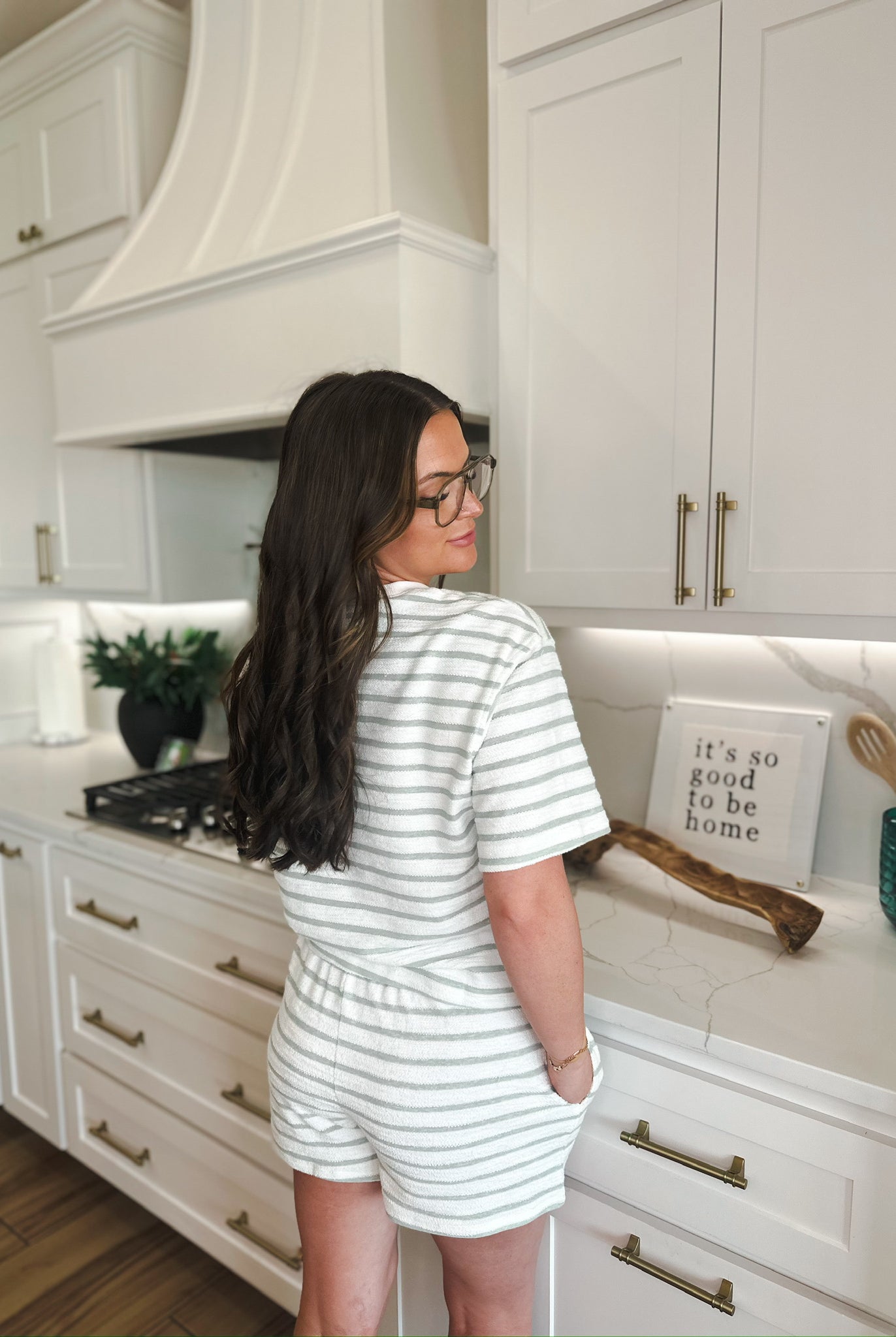 Woman wearing a white and sage green striped loungewear set with shorts and a short-sleeved top. The set is textured and