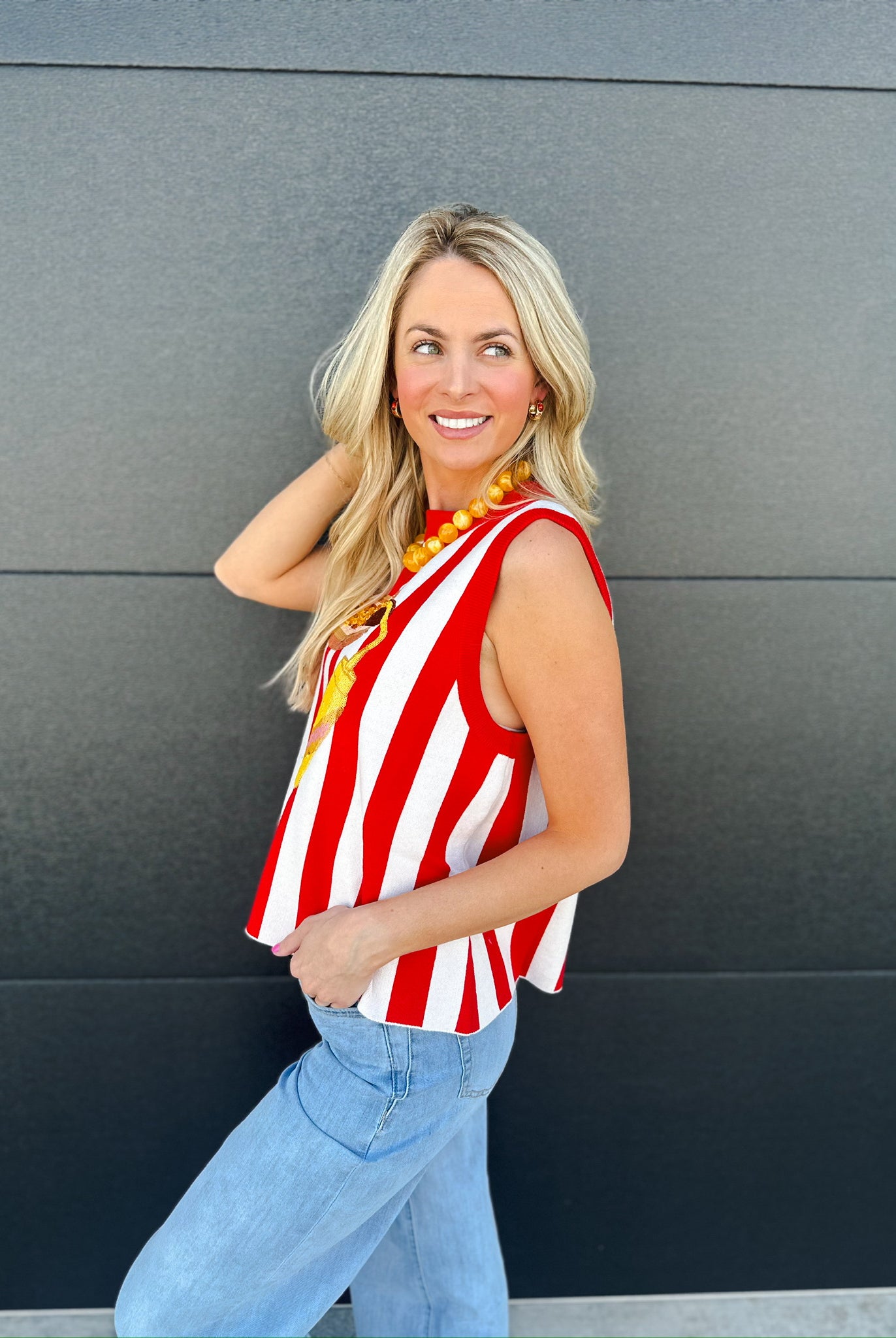 Queen of Sparkles red and white striped knit tank top with a hotdog graphic. Woman wearing light wash jeans.