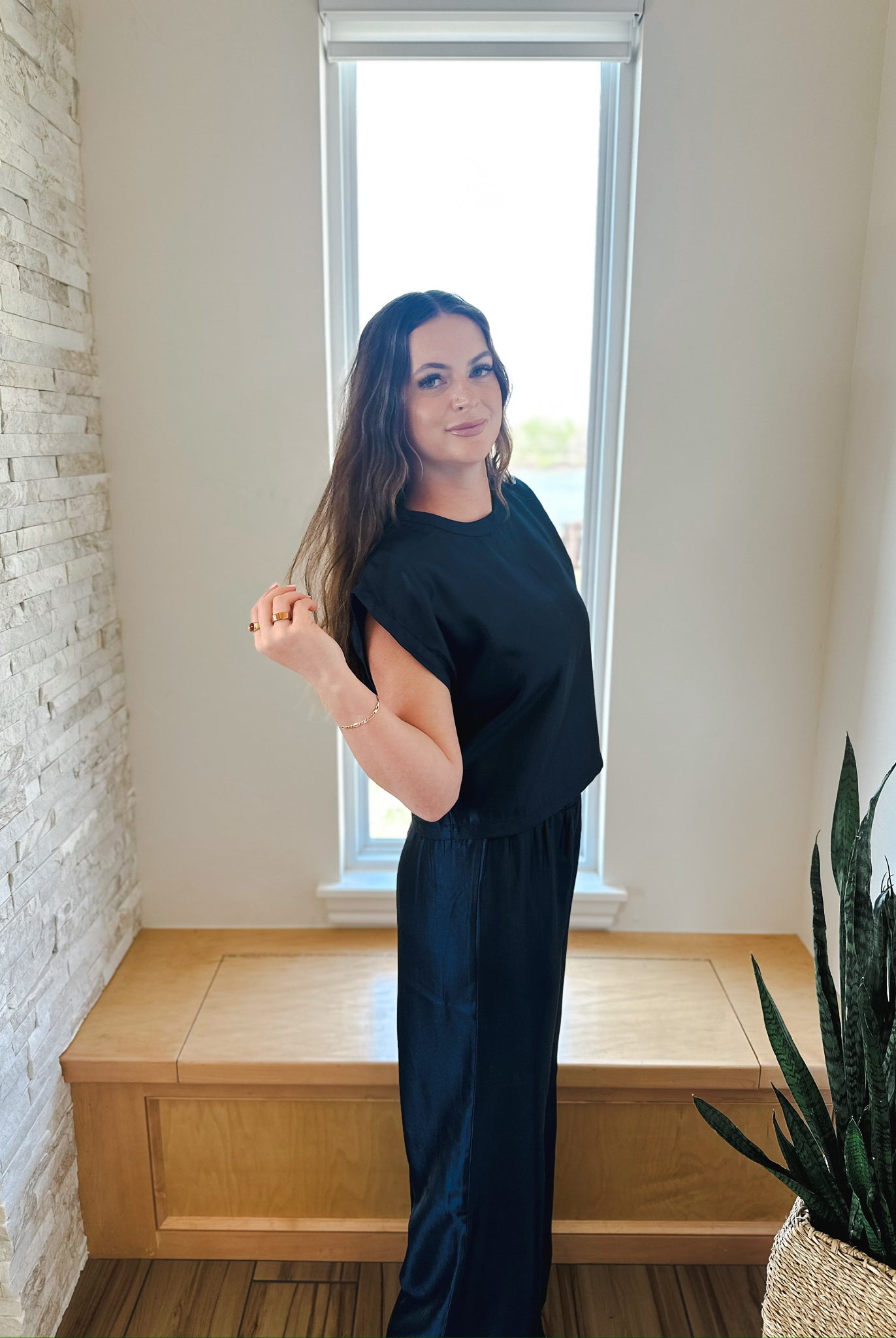Woman in black shimmer matching set: short-sleeve top and wide-leg pants.