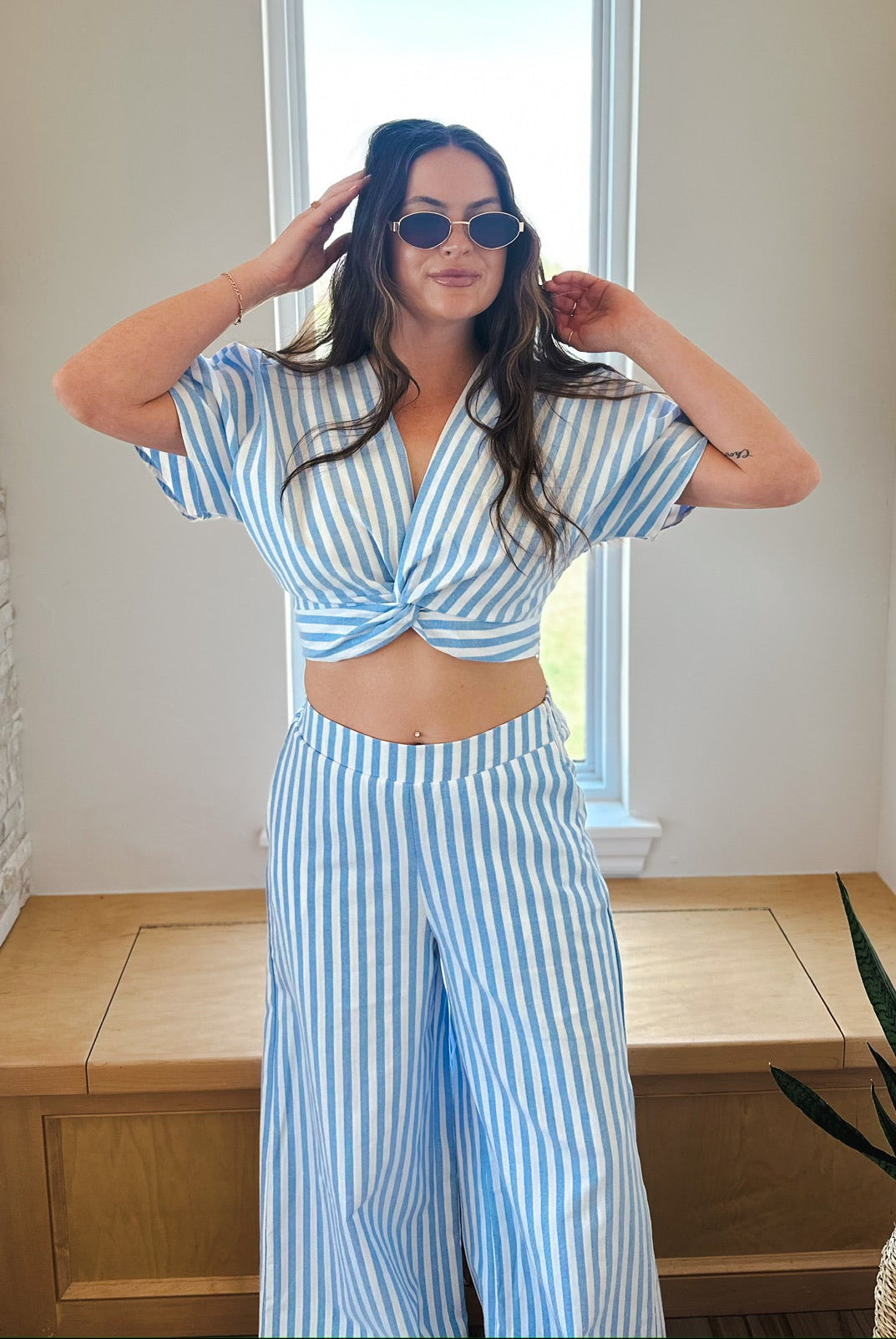 Woman wearing a blue and white striped twist front crop top and matching wide-leg pants set. pants.