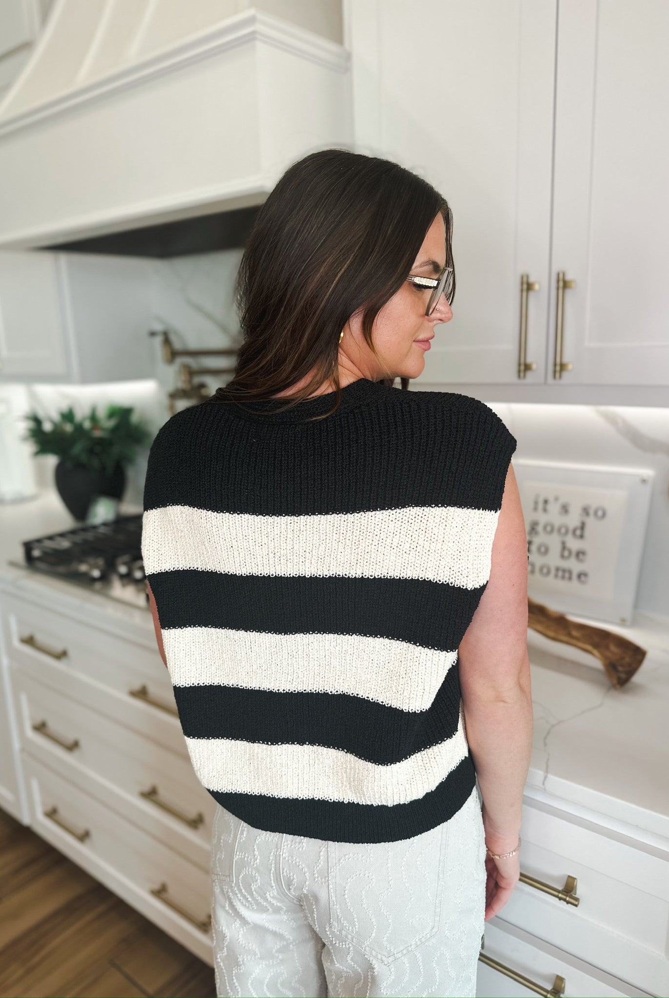 Back view of a women's preppy black and cream horizontal striped knit sweater vest.
