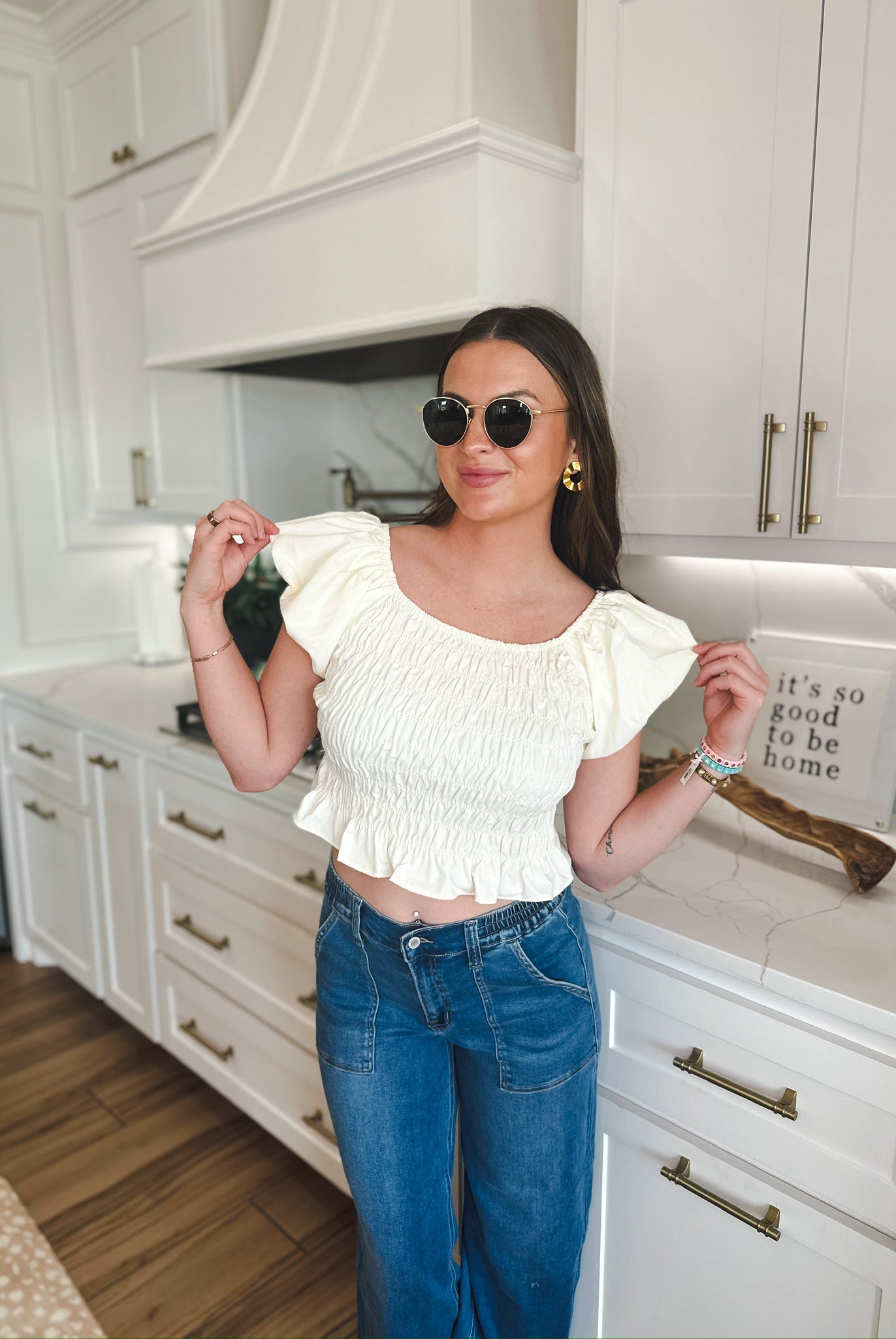 Cream ruched puff sleeve crop top with elasticated hem, paired with mid-rise blue denim cargo pants. Model wears sunglasses