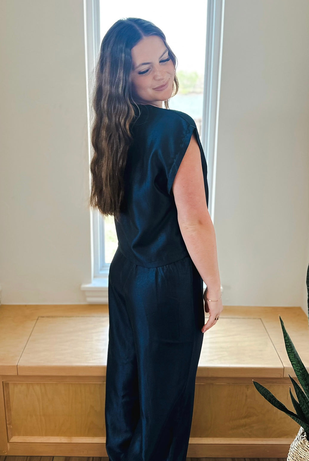 Woman wearing a navy shimmer matching set featuring a short sleeve top and wide-leg pants.