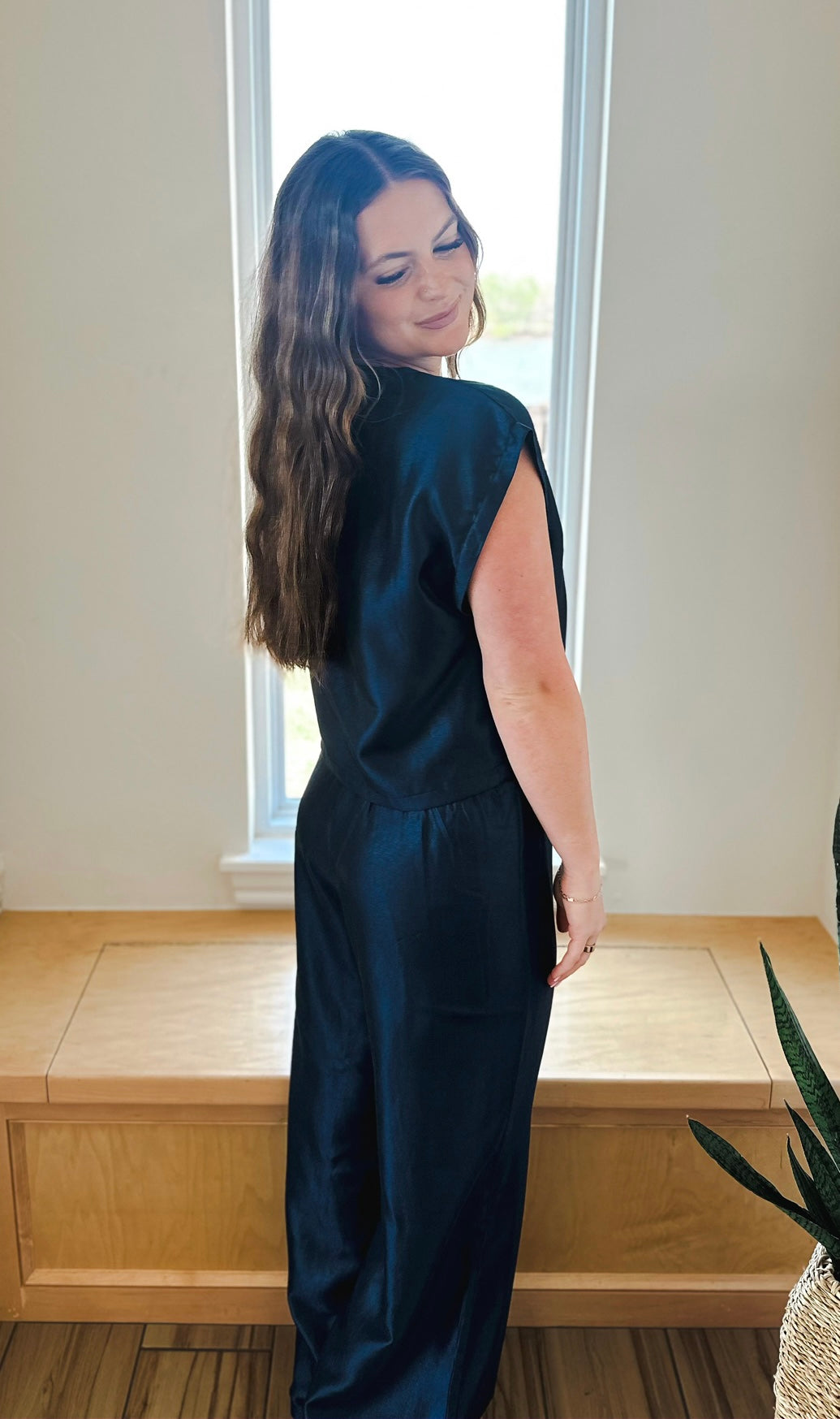 Woman wearing a navy shimmer matching set featuring a short sleeve top and wide-leg pants.