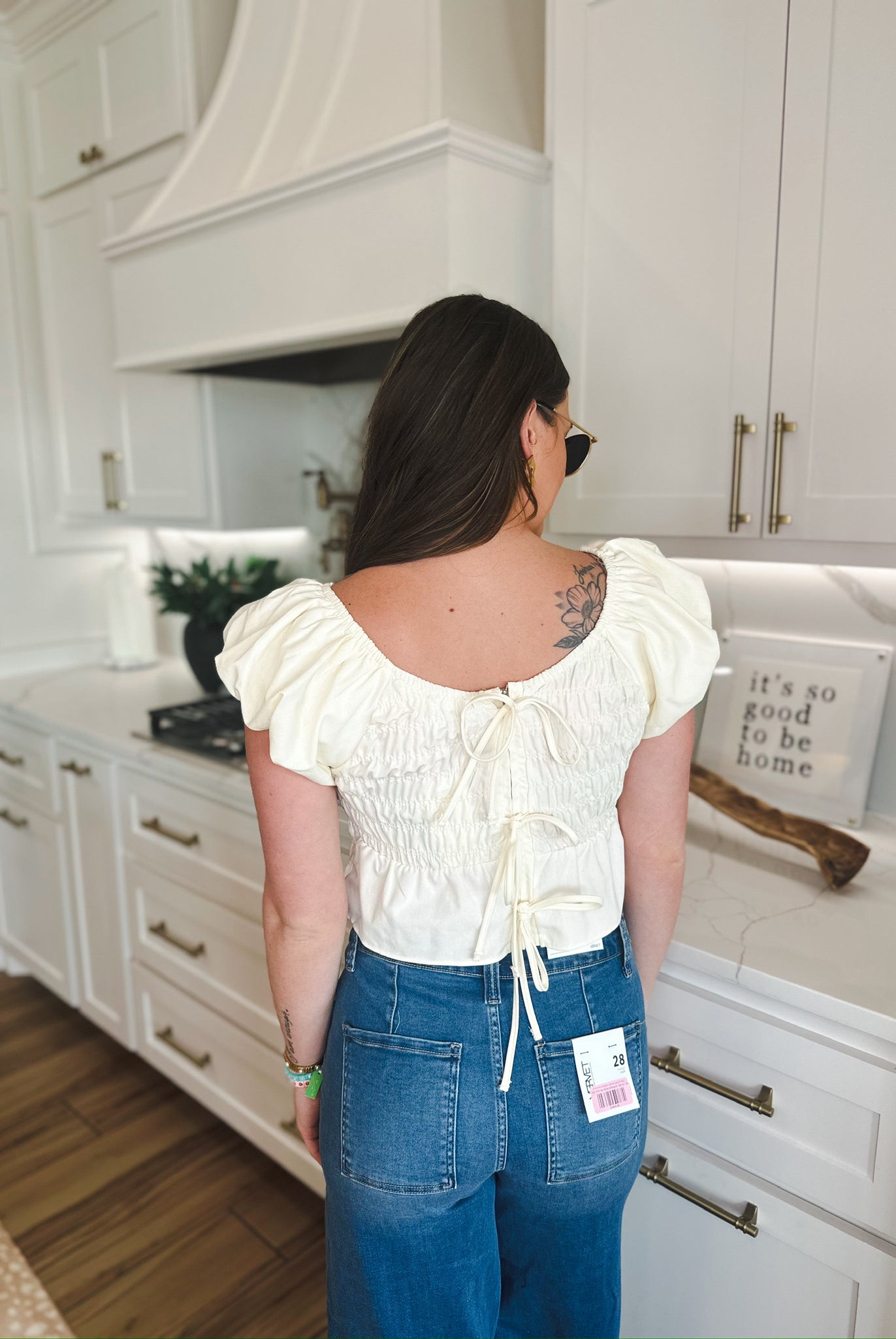 Soft yellow puff sleeve ruched blouse with back tie closure, worn with blue denim jeans.