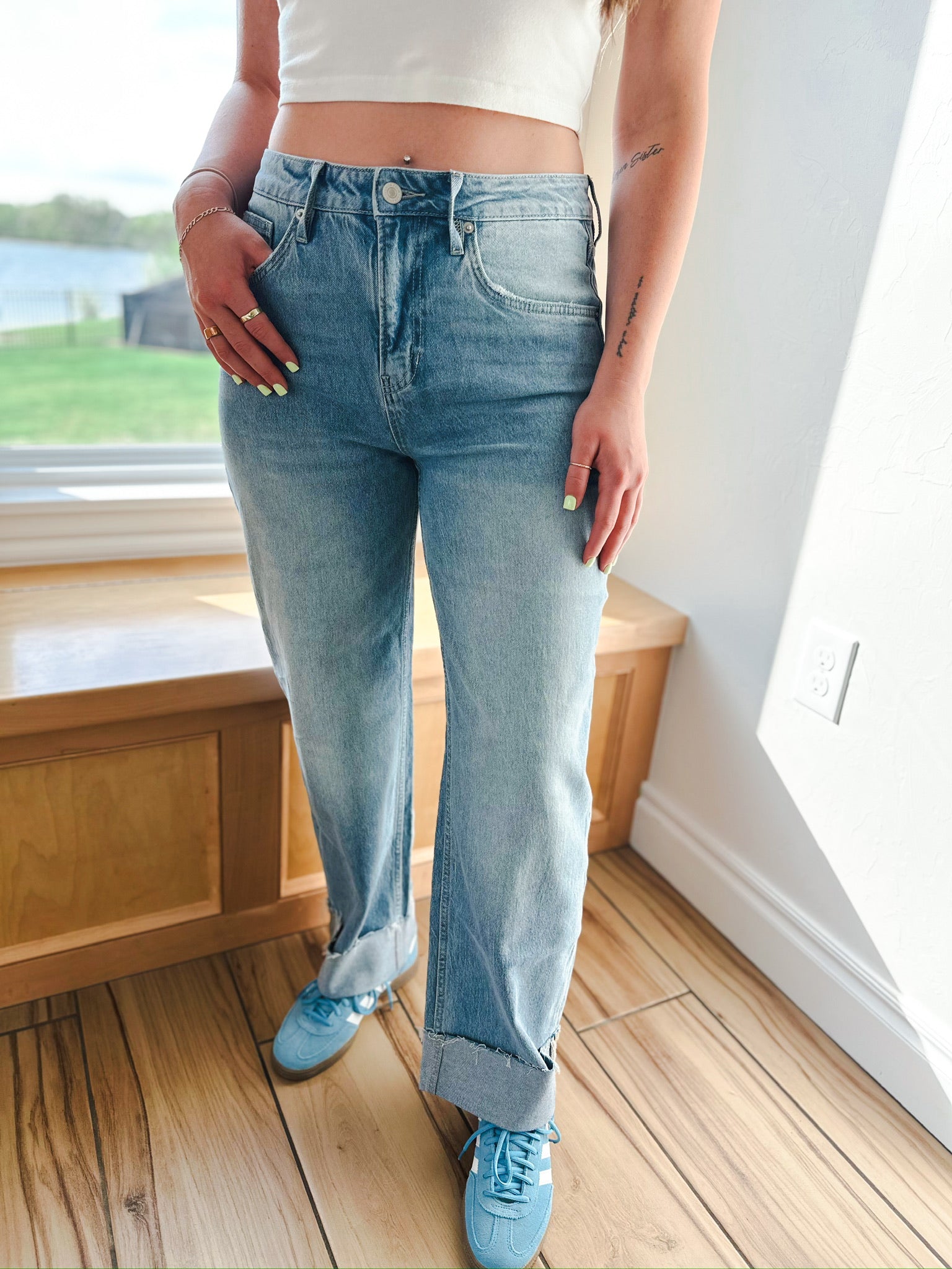 Light wash barrel jeans with cuffed hems, worn by a person with light green nail polish and rings.