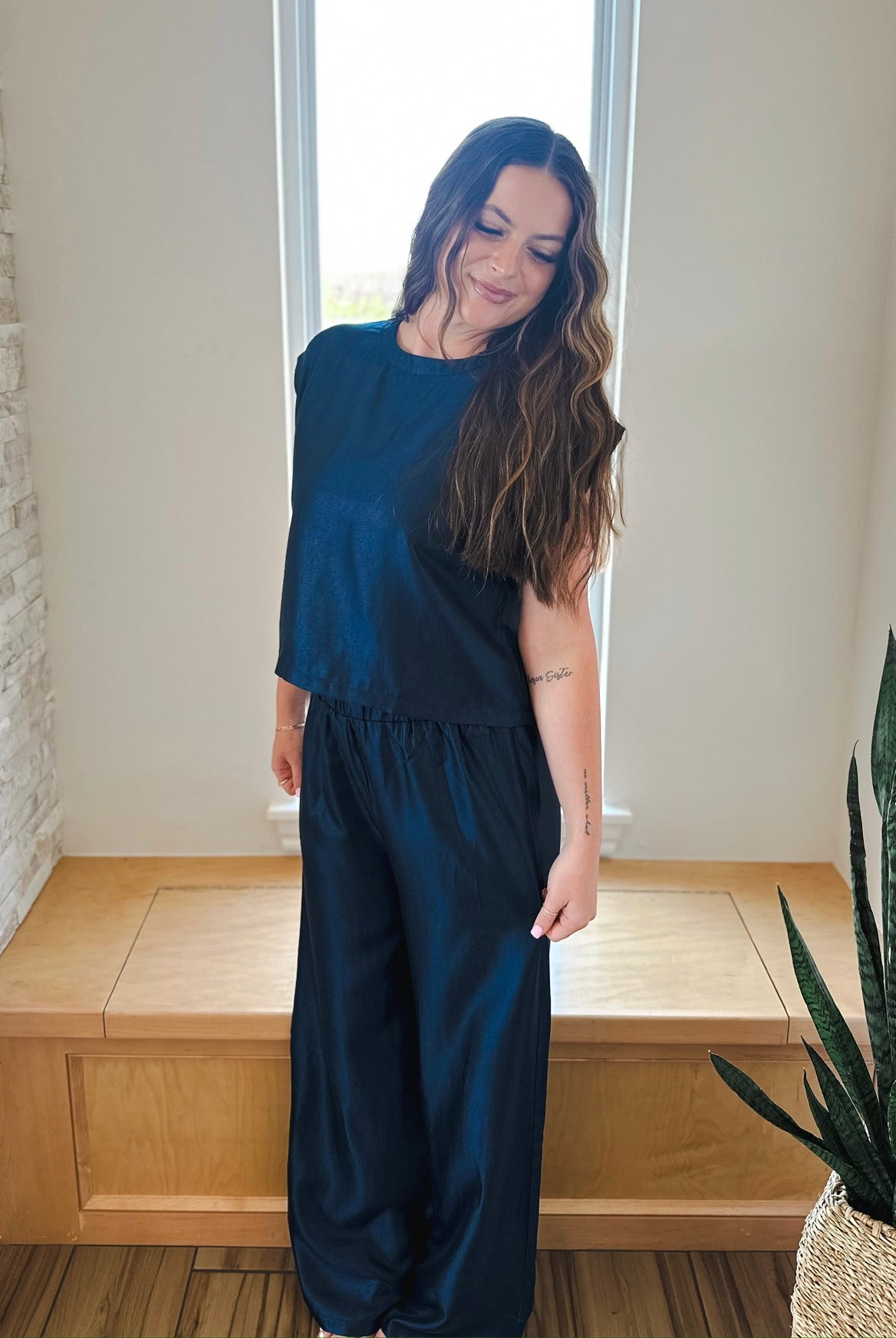Woman wearing a navy shimmer matching set: short sleeve top and wide-leg pants. Elevate your style.