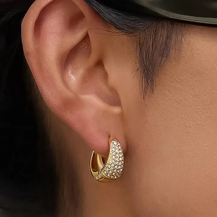 Aurven 18K gold teardrop hoop earrings with pave crystal detailing on a model's ear.