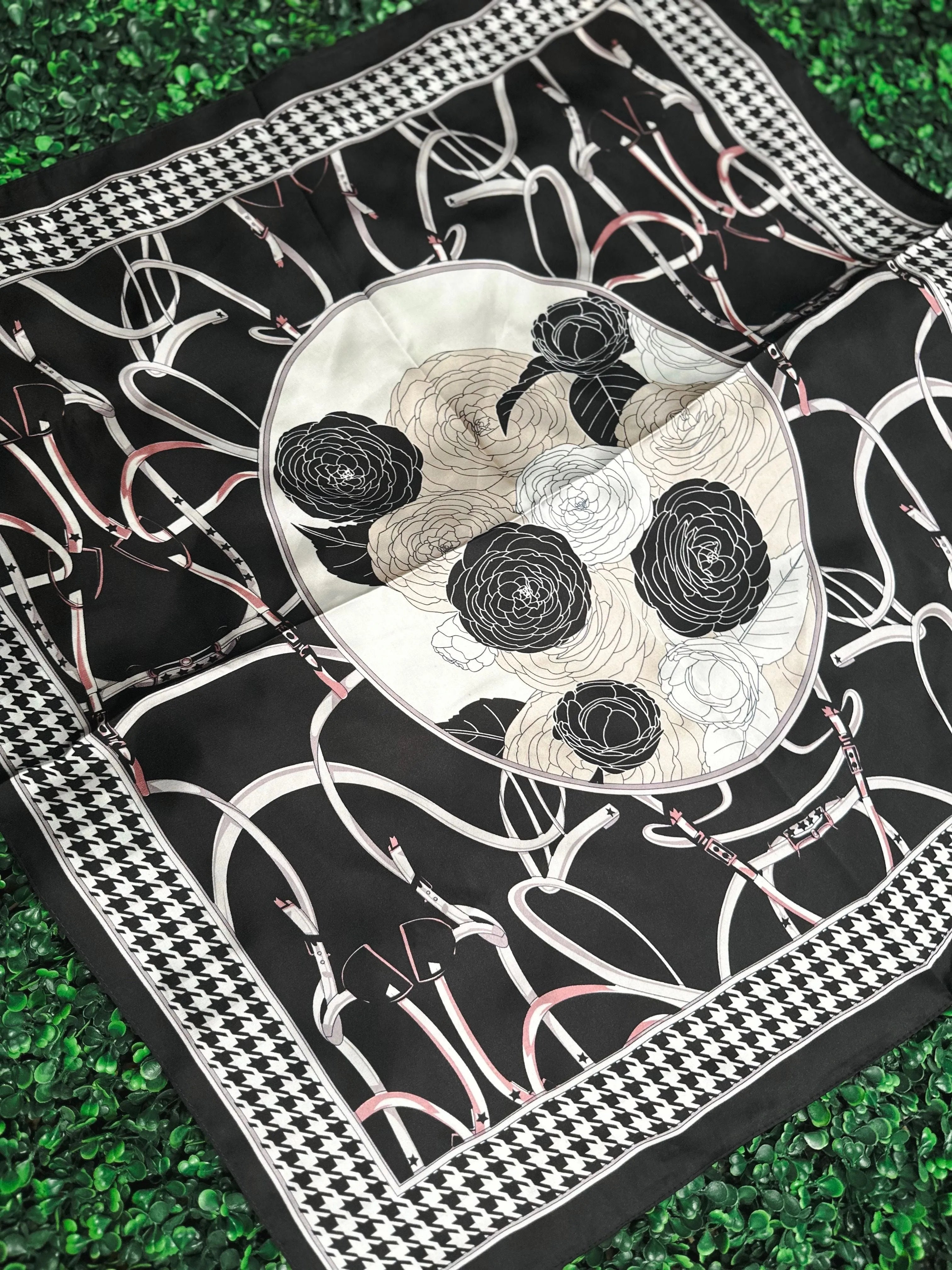 Black and white floral scarf with a central circle of roses and a checkered border. Features belt and buckle motifs.