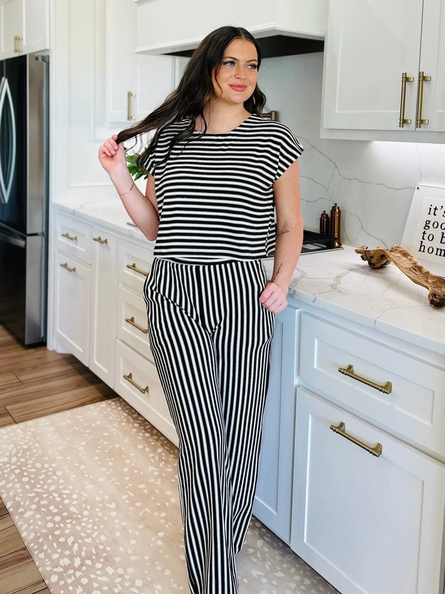 Woman wearing a black and cream striped knit matching set, featuring a cropped short-sleeve top and wide-leg pants.