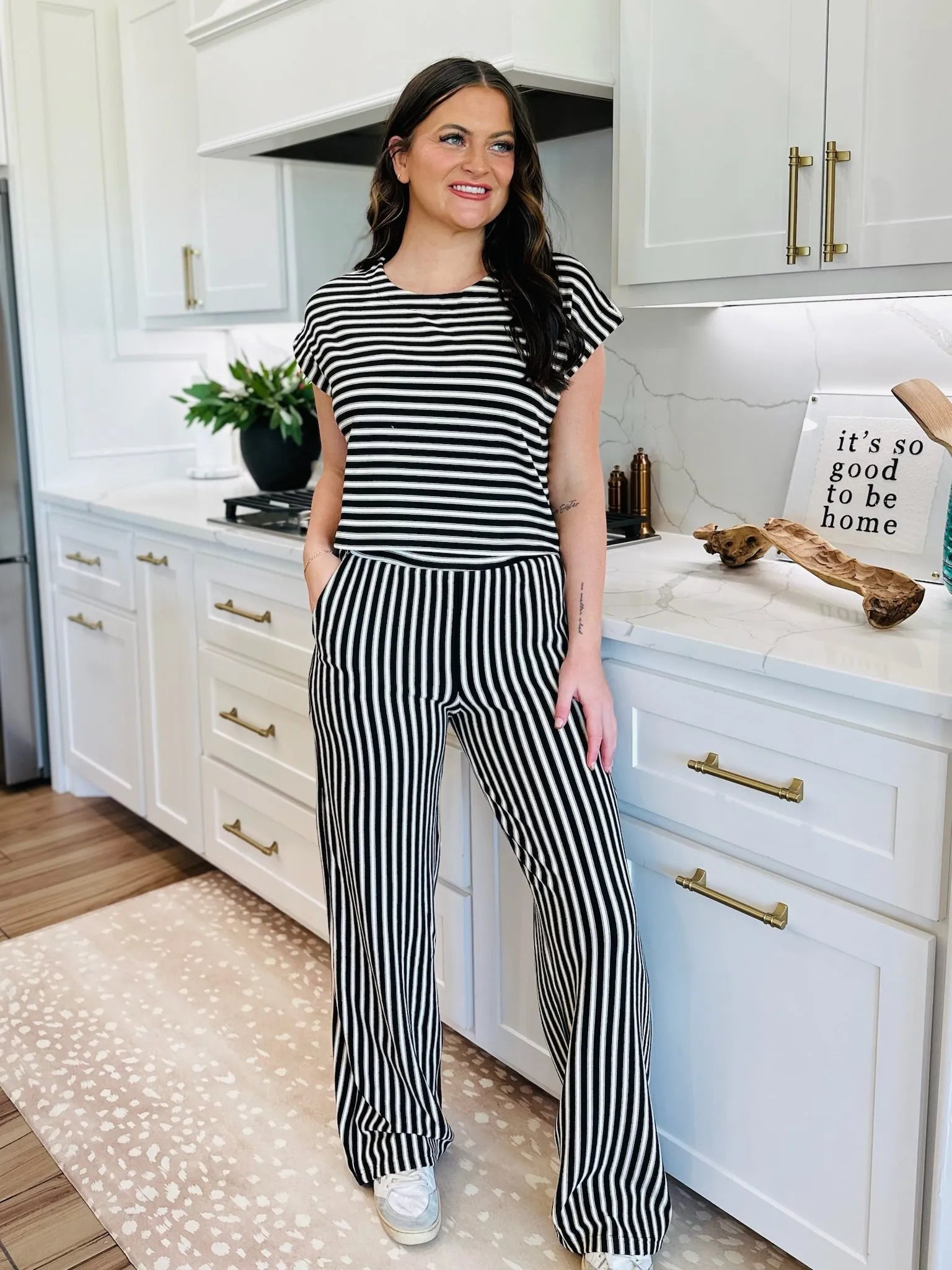 Woman in black and cream striped knit matching set, featuring a short-sleeve top and wide-leg pants.