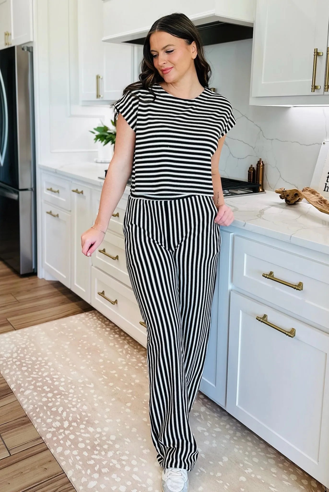Woman wearing a black and white striped knit t-shirt and matching wide-leg pants. Standing in a kitchen.