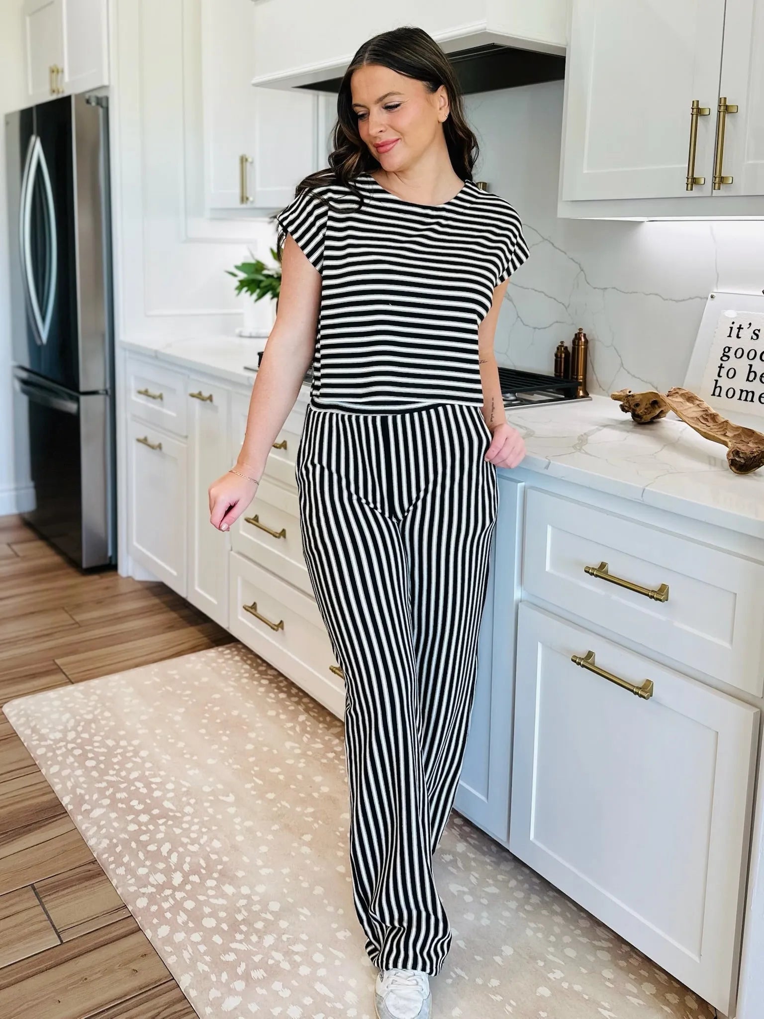 Woman wearing a black and white striped knit t-shirt and matching wide-leg pants. Standing in a kitchen.