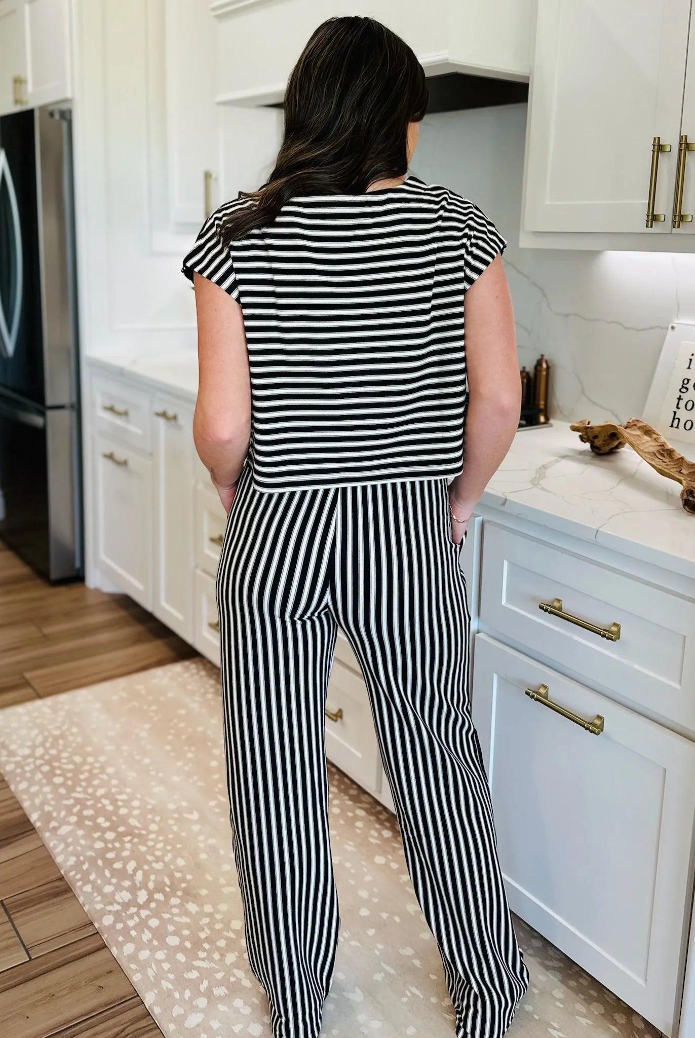 Woman wearing a black and cream striped knit matching set, featuring a short-sleeve top and wide-leg pants.