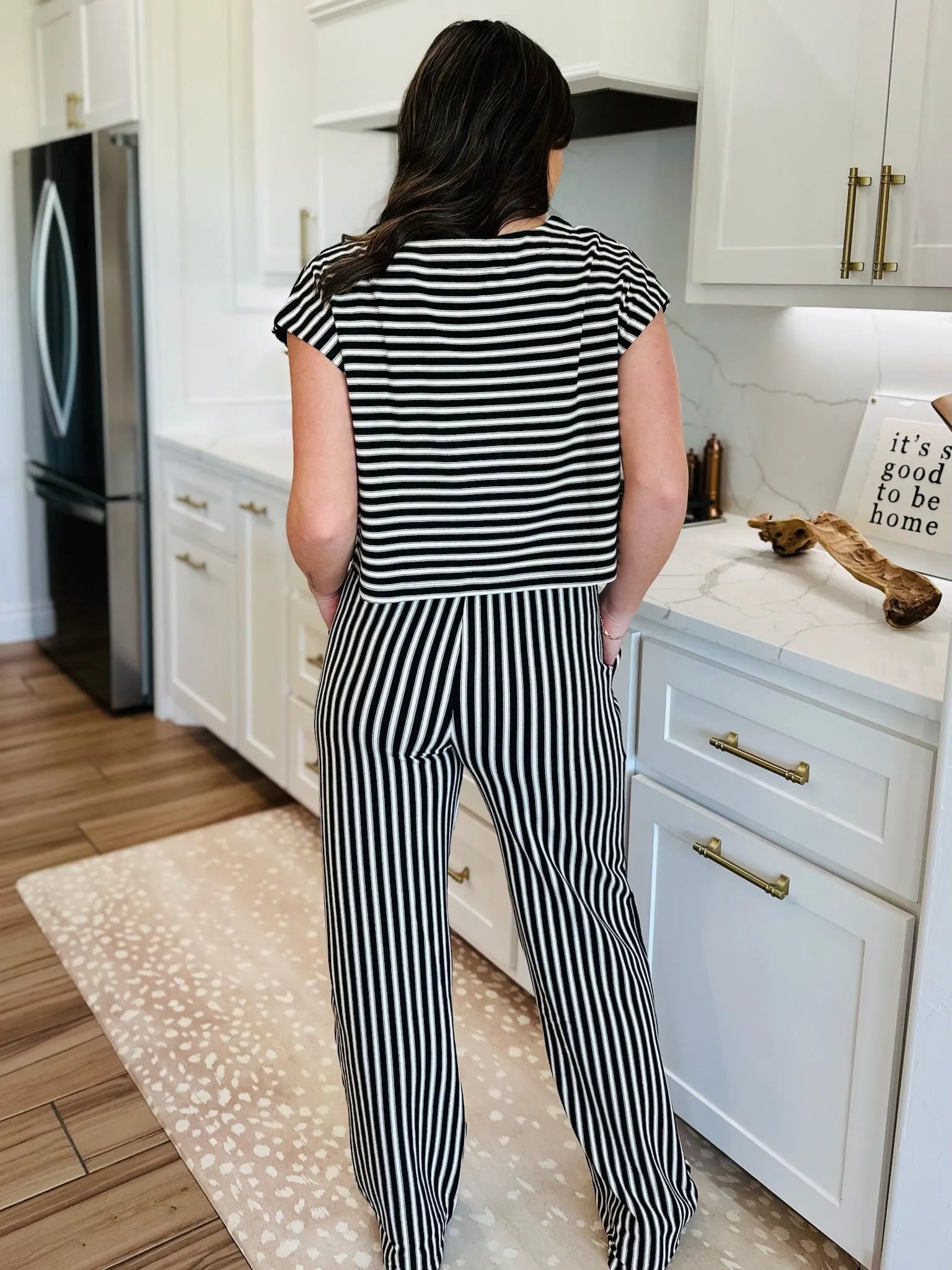 Woman wearing a black and cream striped knit matching set, featuring a short-sleeve top and wide-leg pants.