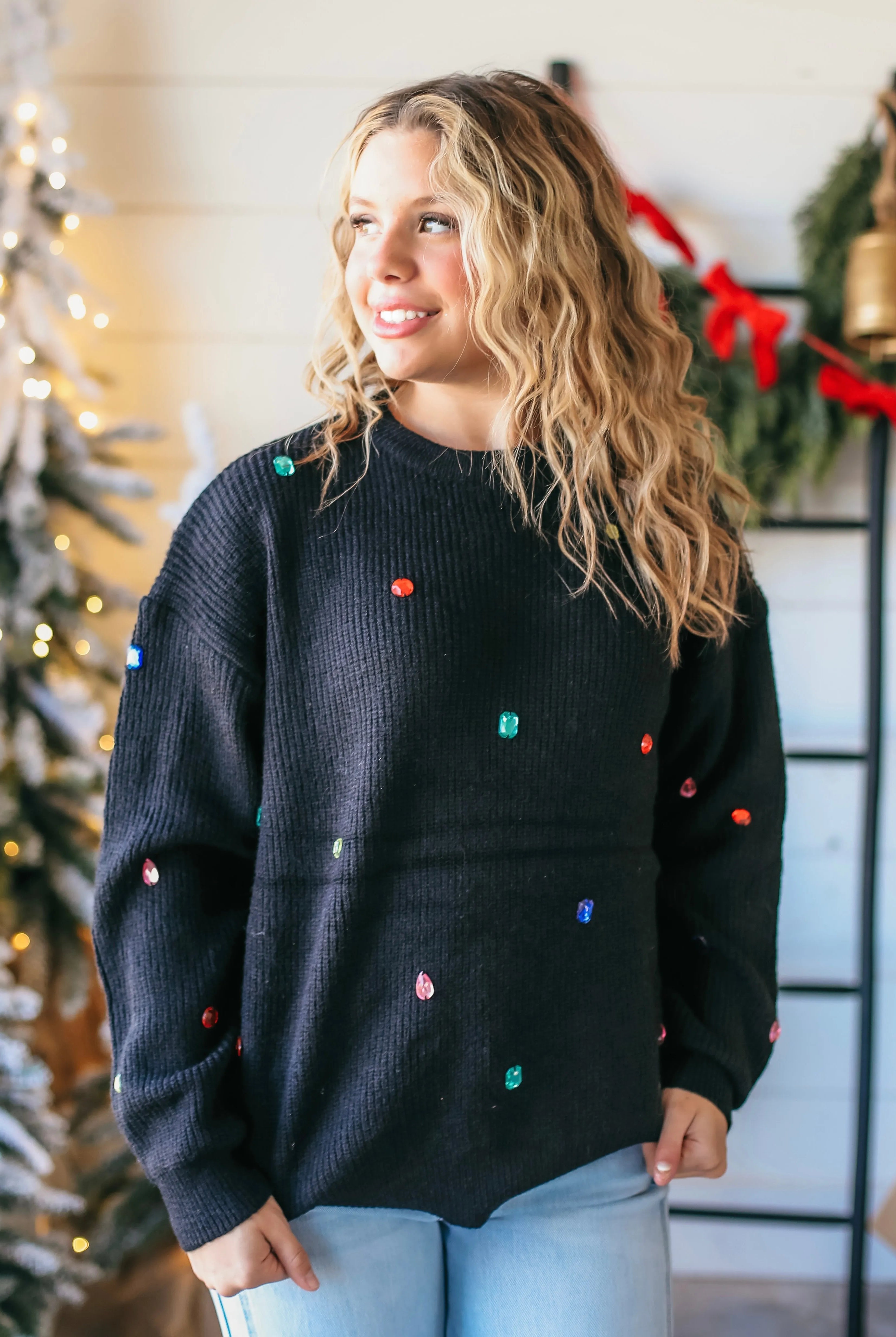 Black crewneck sweater with scattered multi-color jewels. Ribbed knit texture. Perfect for festive occasions.
