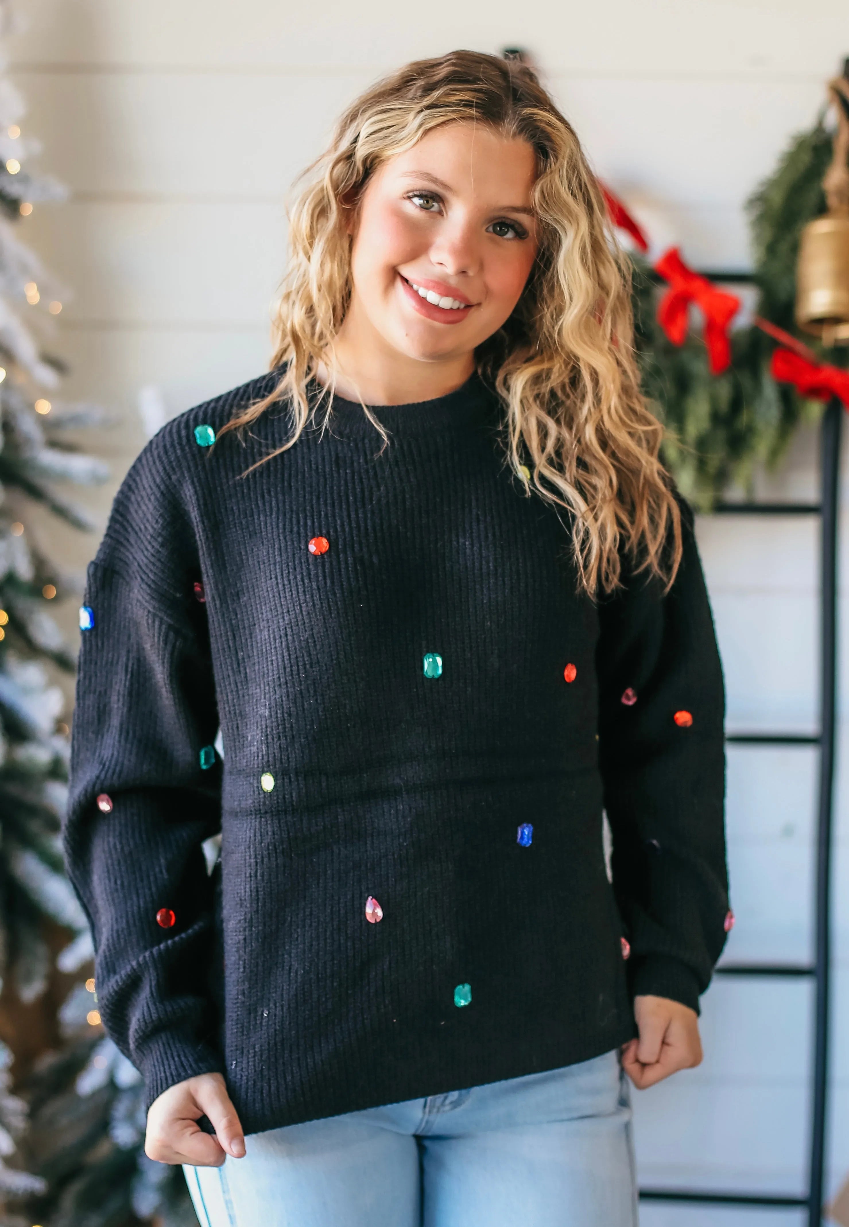 Black knit sweater adorned with colorful, faceted jewels resembling Christmas lights.