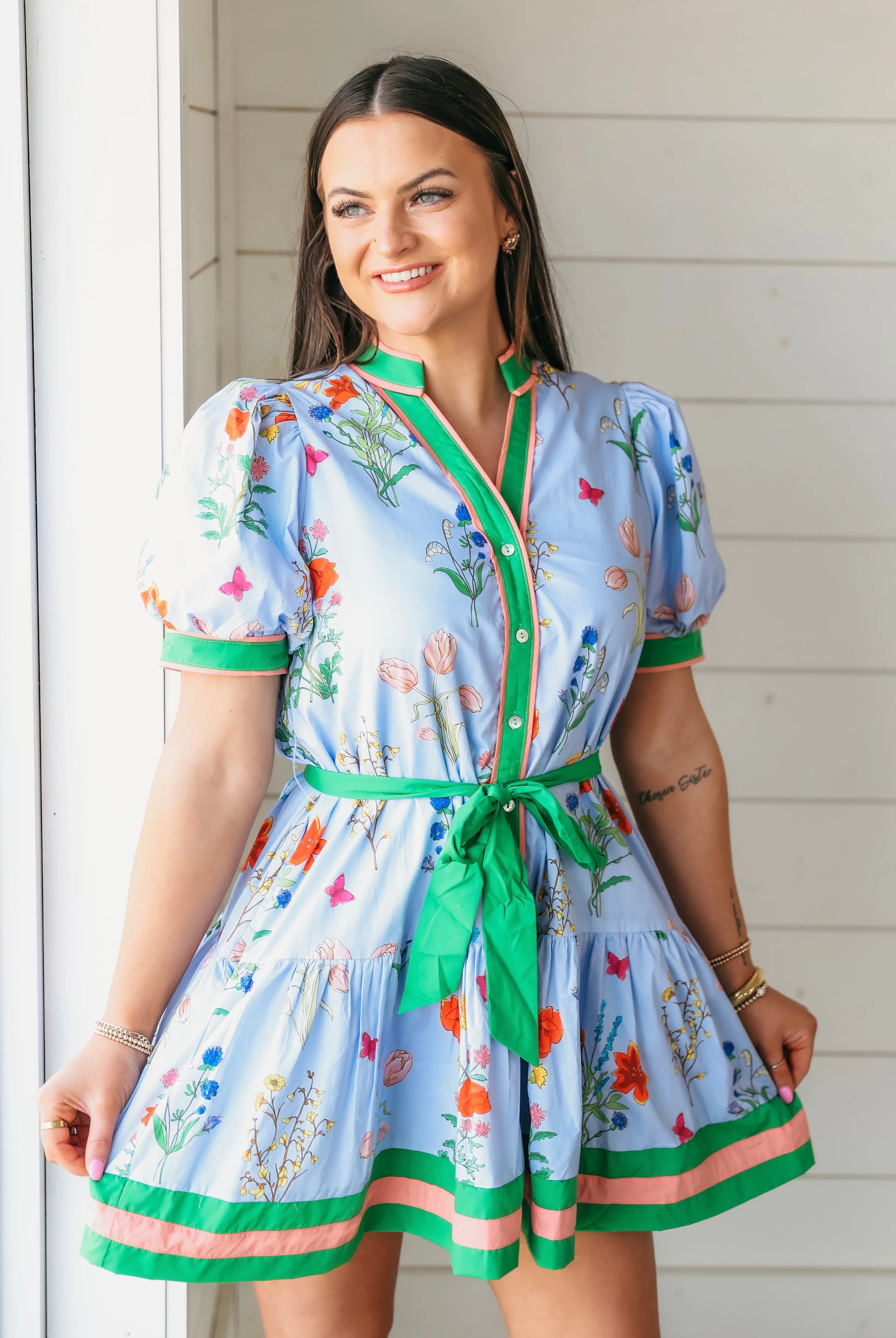 Blue Entro floral button down dress with green tie belt. Features a print of colorful flowers and butterflies, with green