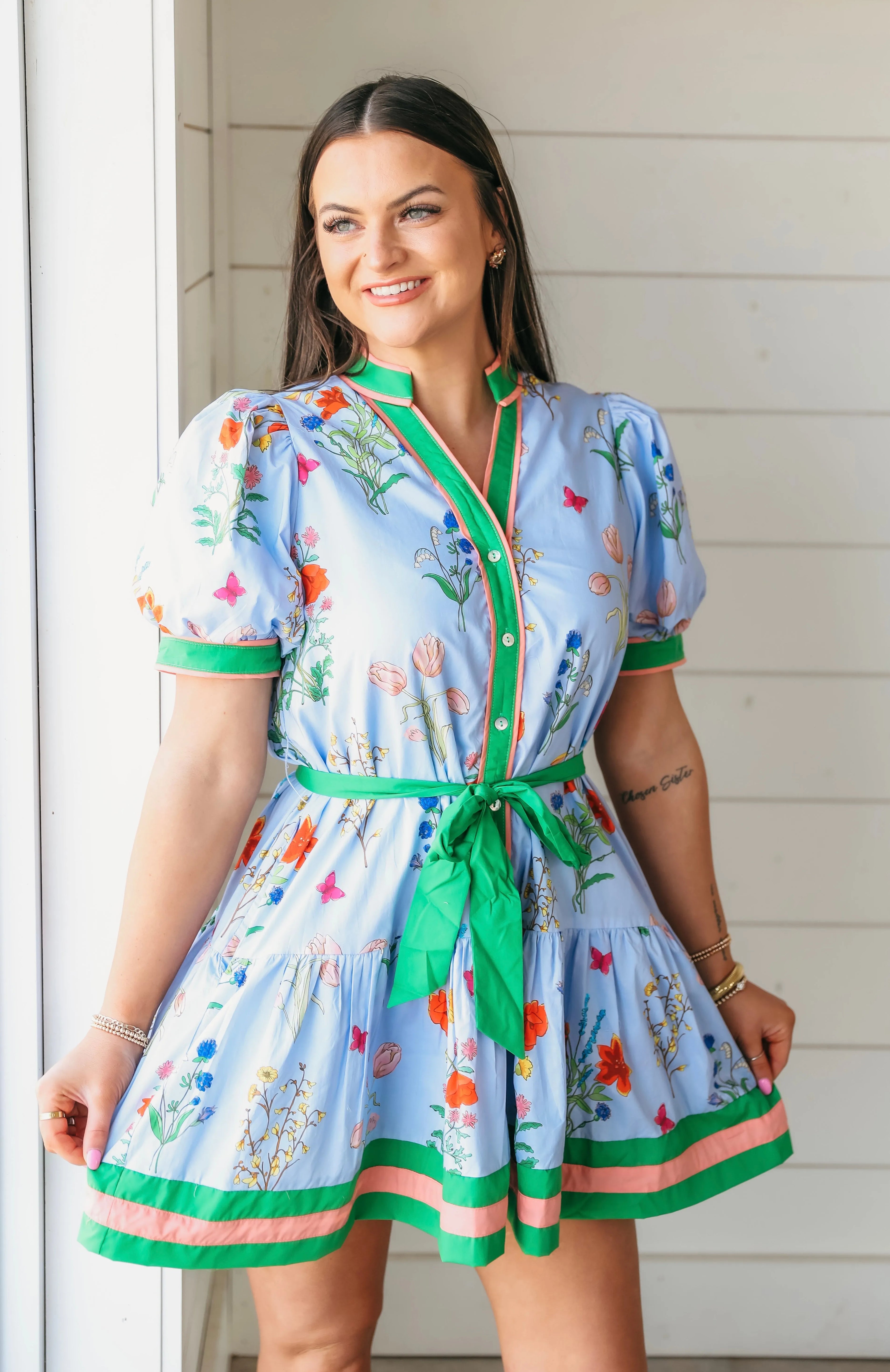 Blue Entro floral button down dress with green tie belt. Features a print of colorful flowers and butterflies, with green