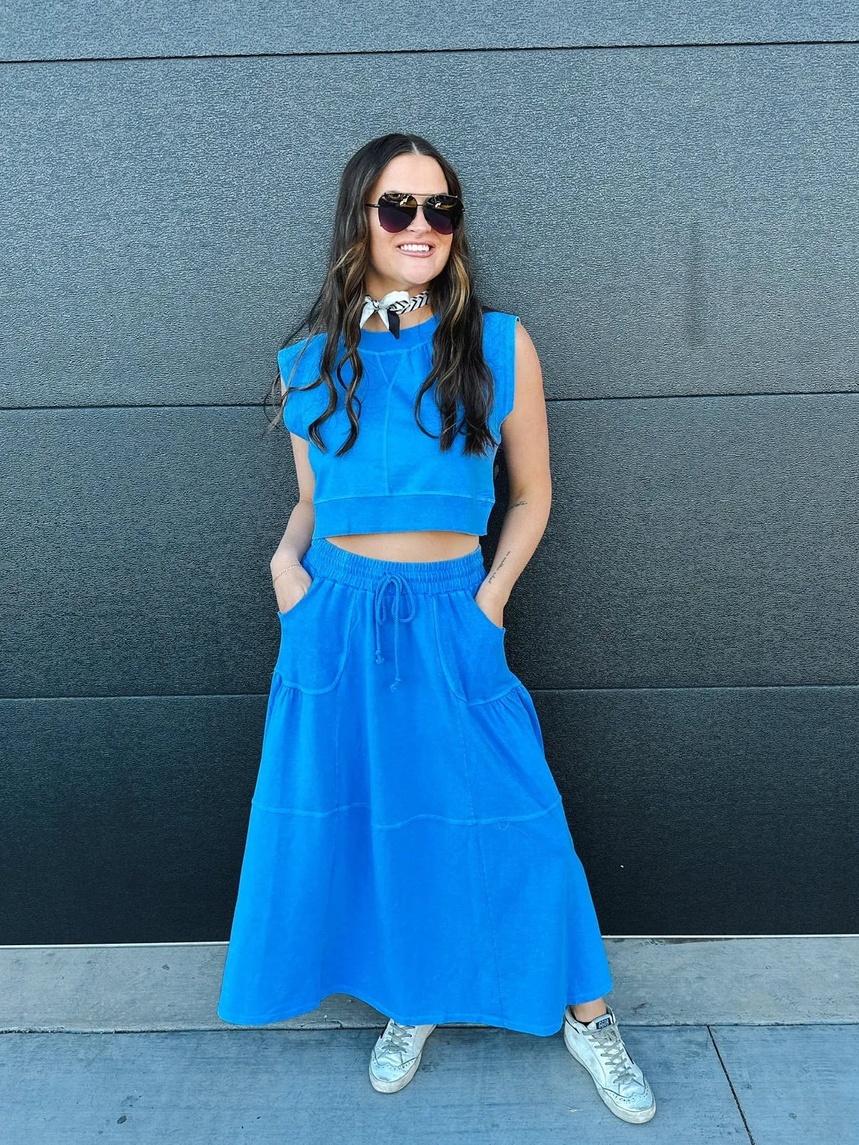 Bright blue sleeveless crop top and tiered maxi skirt set with drawstring waist and pockets, worn by a woman with