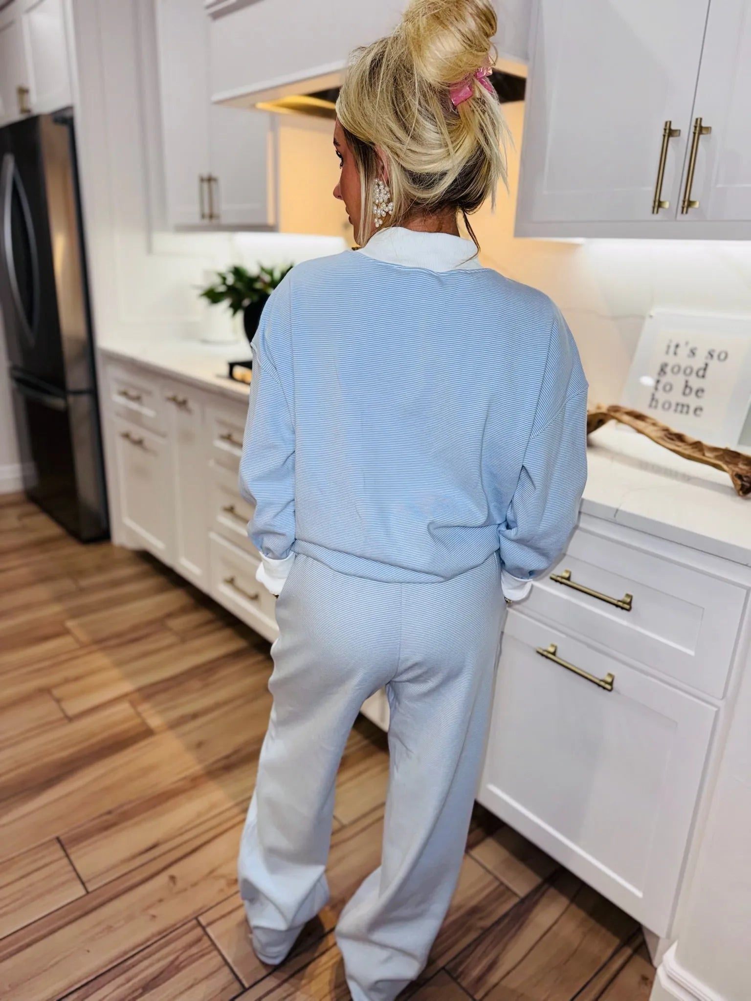 Back view of woman wearing light blue striped active sweatpants and matching long-sleeved shirt with white collar.