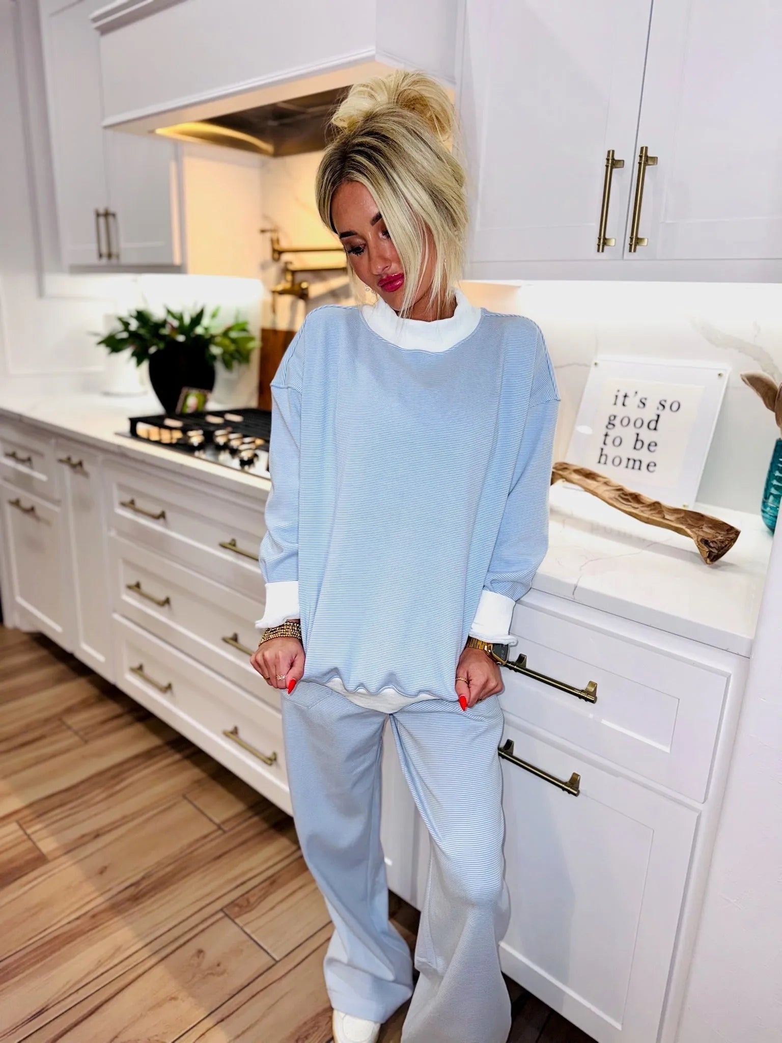 Light blue striped active sweatpants set with white cuffs and neckline. Woman wearing the outfit indoors.