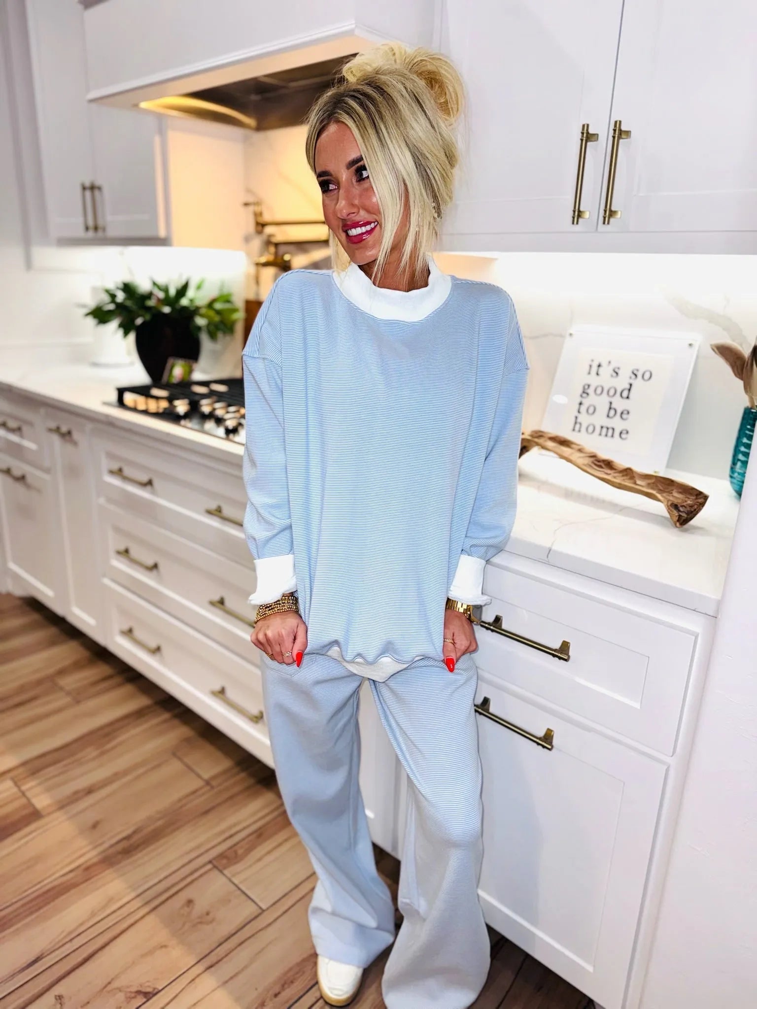Woman wearing a light blue and white striped loungewear set with a mock neck sweatshirt and wide-leg sweatpants.