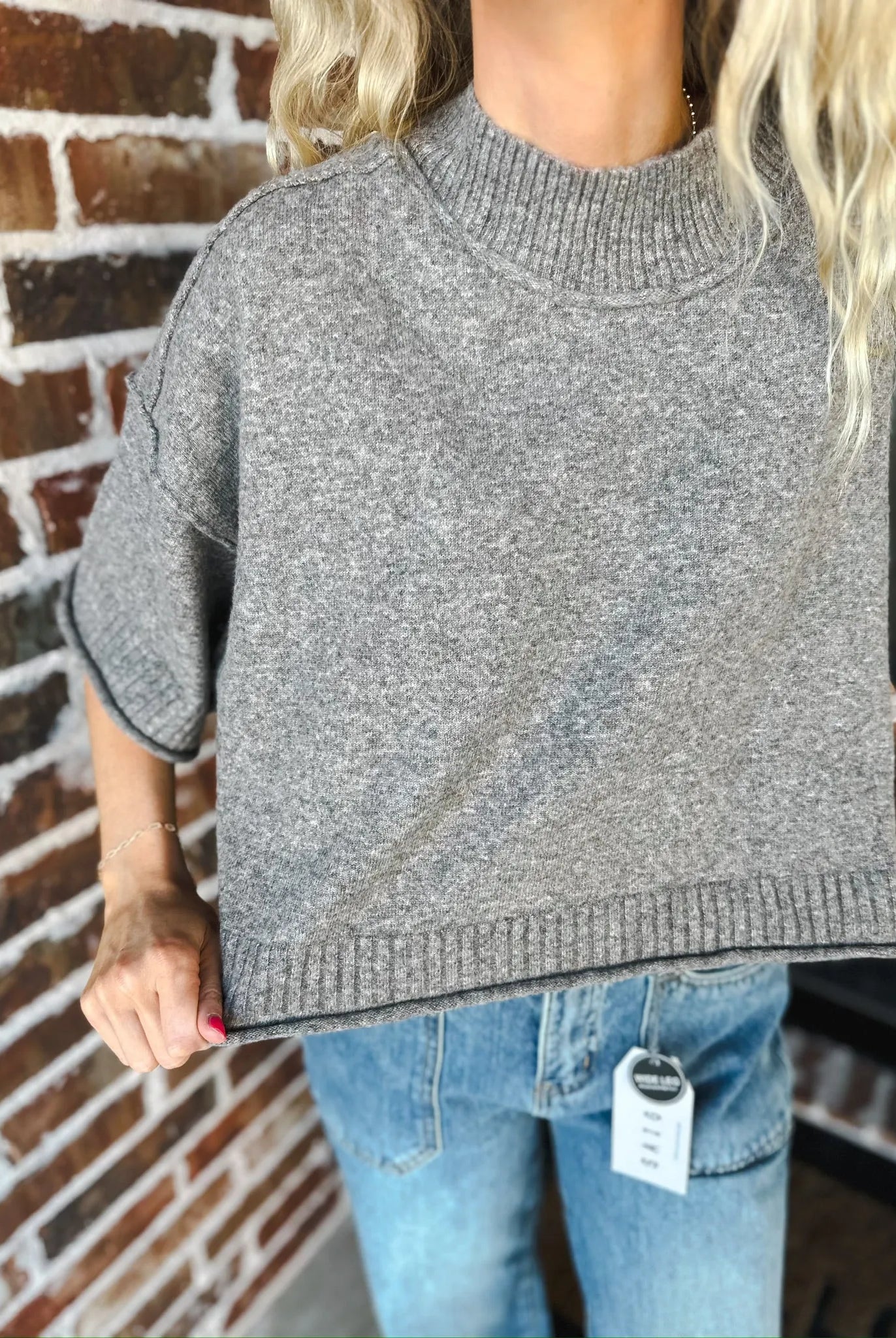 Grey soft knit sweater tee with mock neck and short sleeves. Worn with blue jeans.