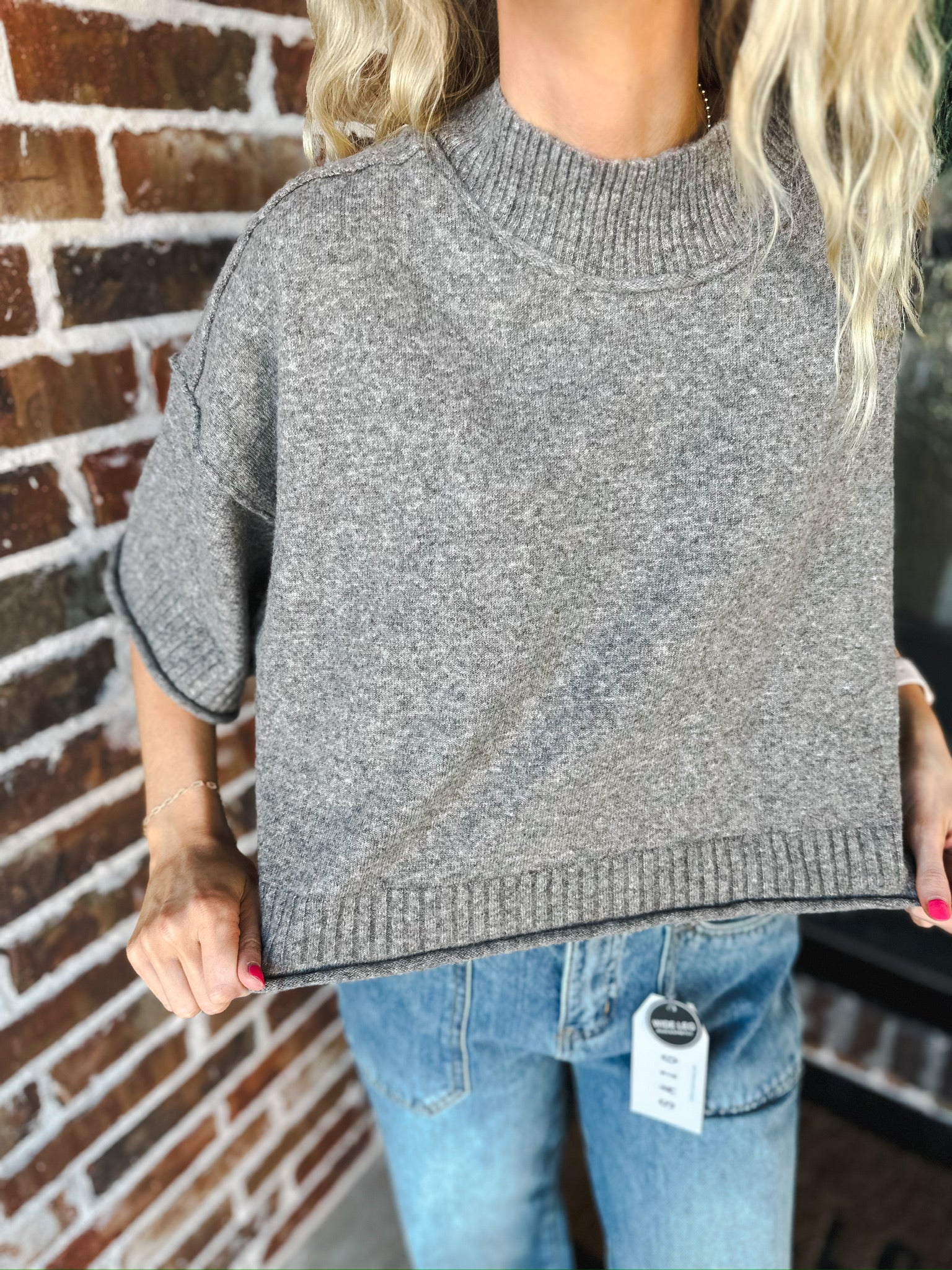 Grey soft knit sweater tee with mock neck and short sleeves. Worn with blue jeans.