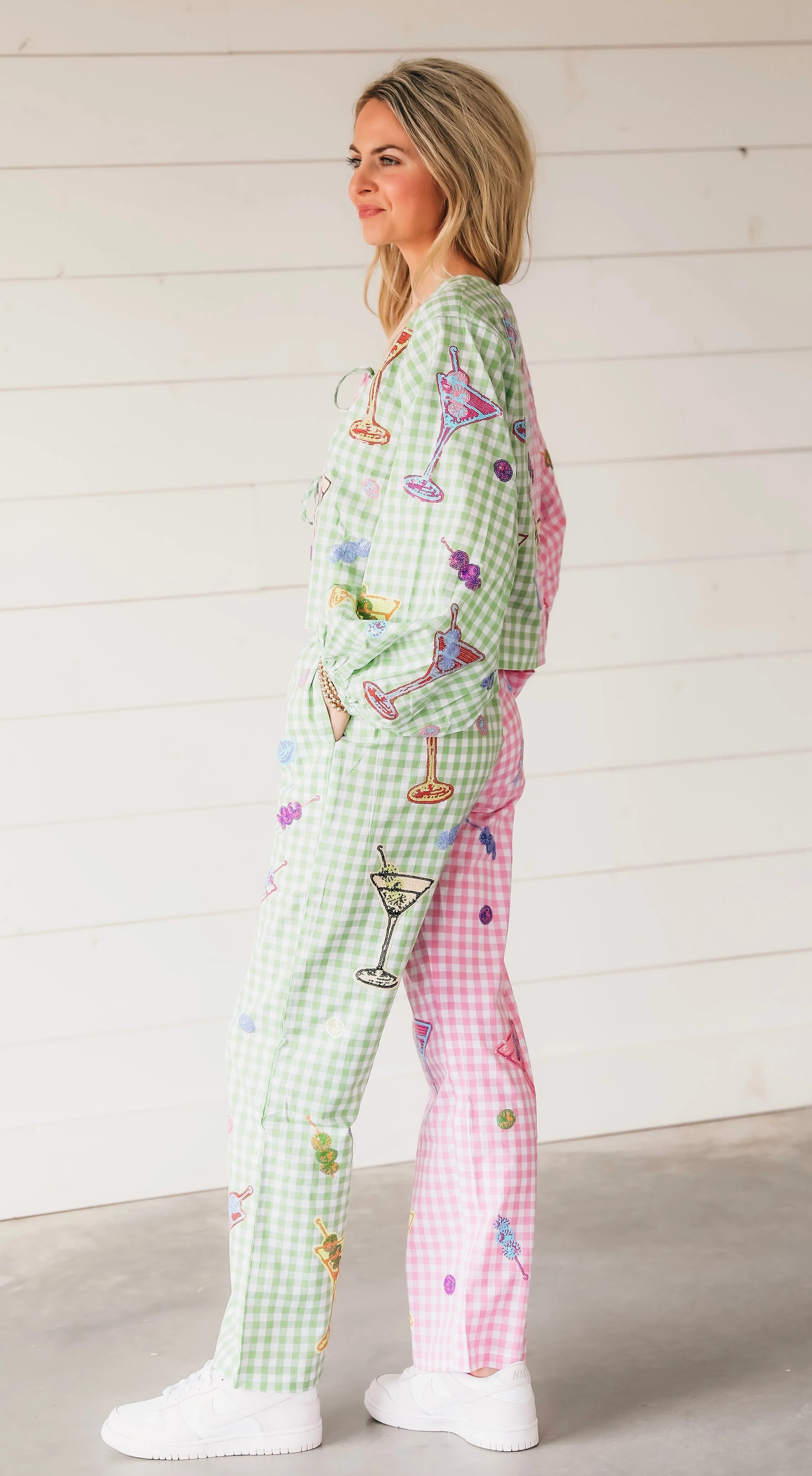 Woman wearing colorblock gingham Martini trousers, green and pink check with martini glass, fruit, and cocktail embroidery.