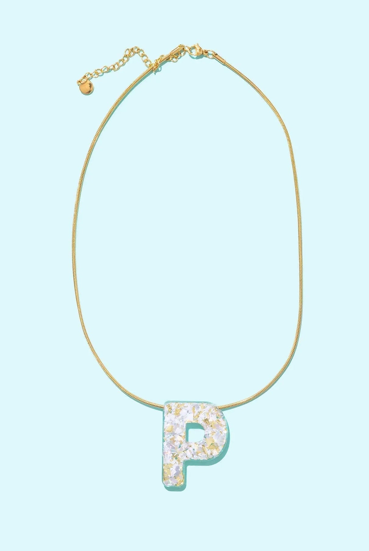Gold chain necklace with a glittery white letter P pendant, resembling confetti.