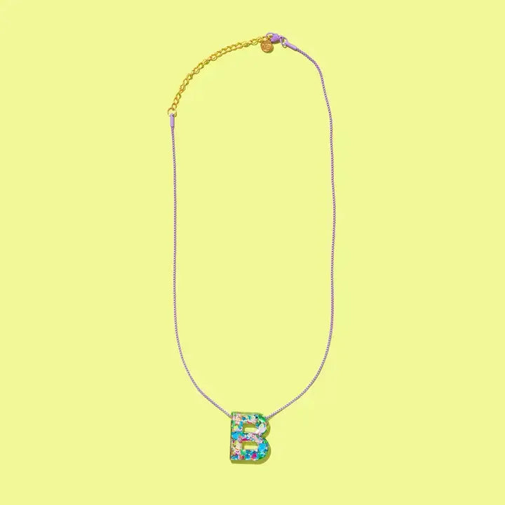 Confetti letter B necklace with a glittery resin pendant on a delicate purple chain with gold accents.
