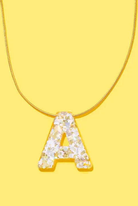 Gold chain necklace with a clear resin letter 'A' pendant filled with iridescent confetti.