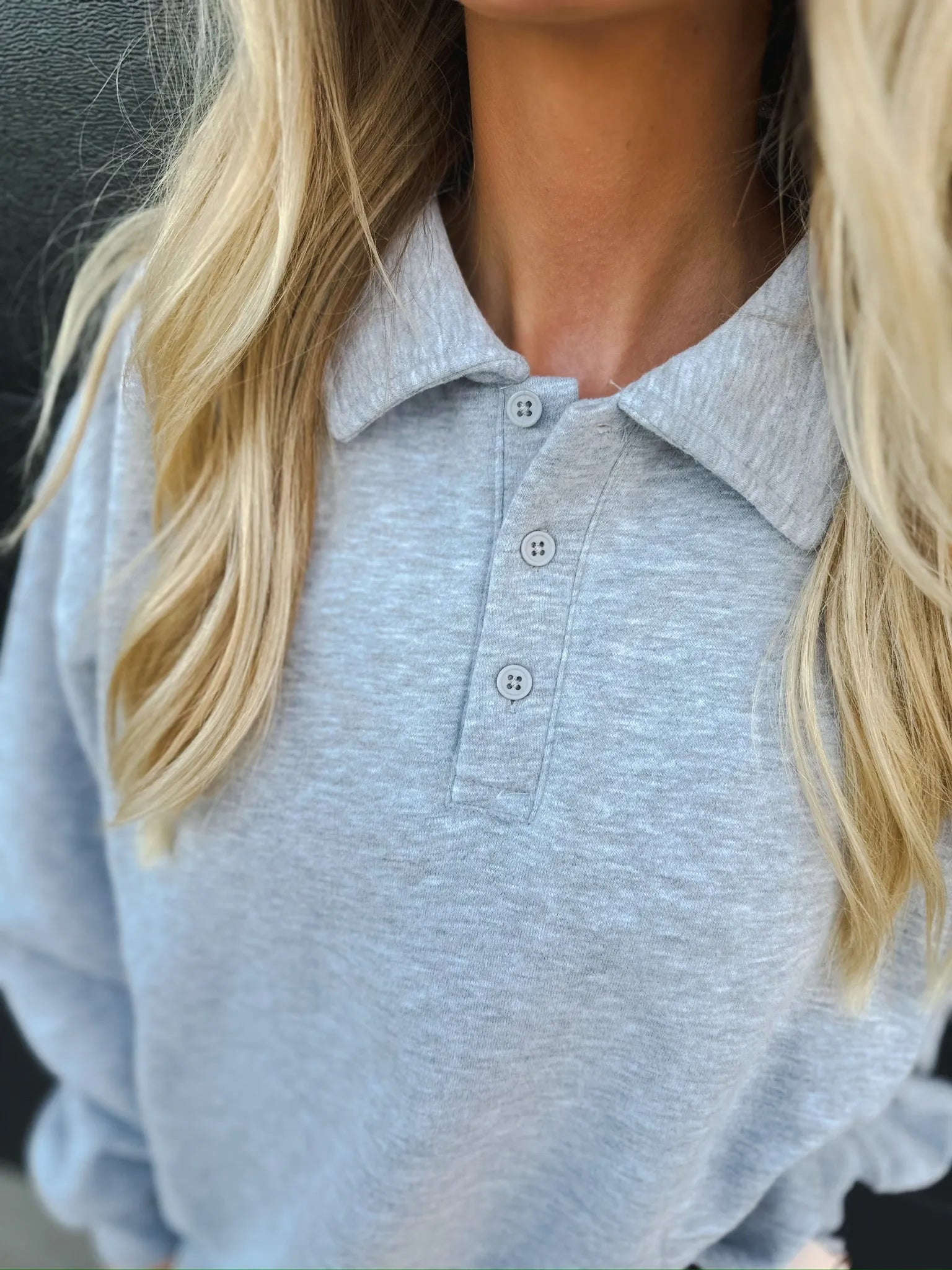 Light grey cozy fleece polo pullover with a collar and three grey buttons down the placket. A woman with blonde hair is