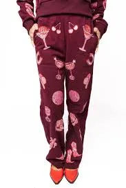 Dark plum sweatpants with a disco cowgirl pattern including cherries, martini glasses, cowboy boots, and abstract circles