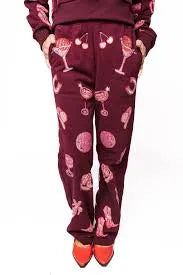 Dark plum sweatpants with a disco cowgirl pattern including cherries, martini glasses, cowboy boots, and abstract circles