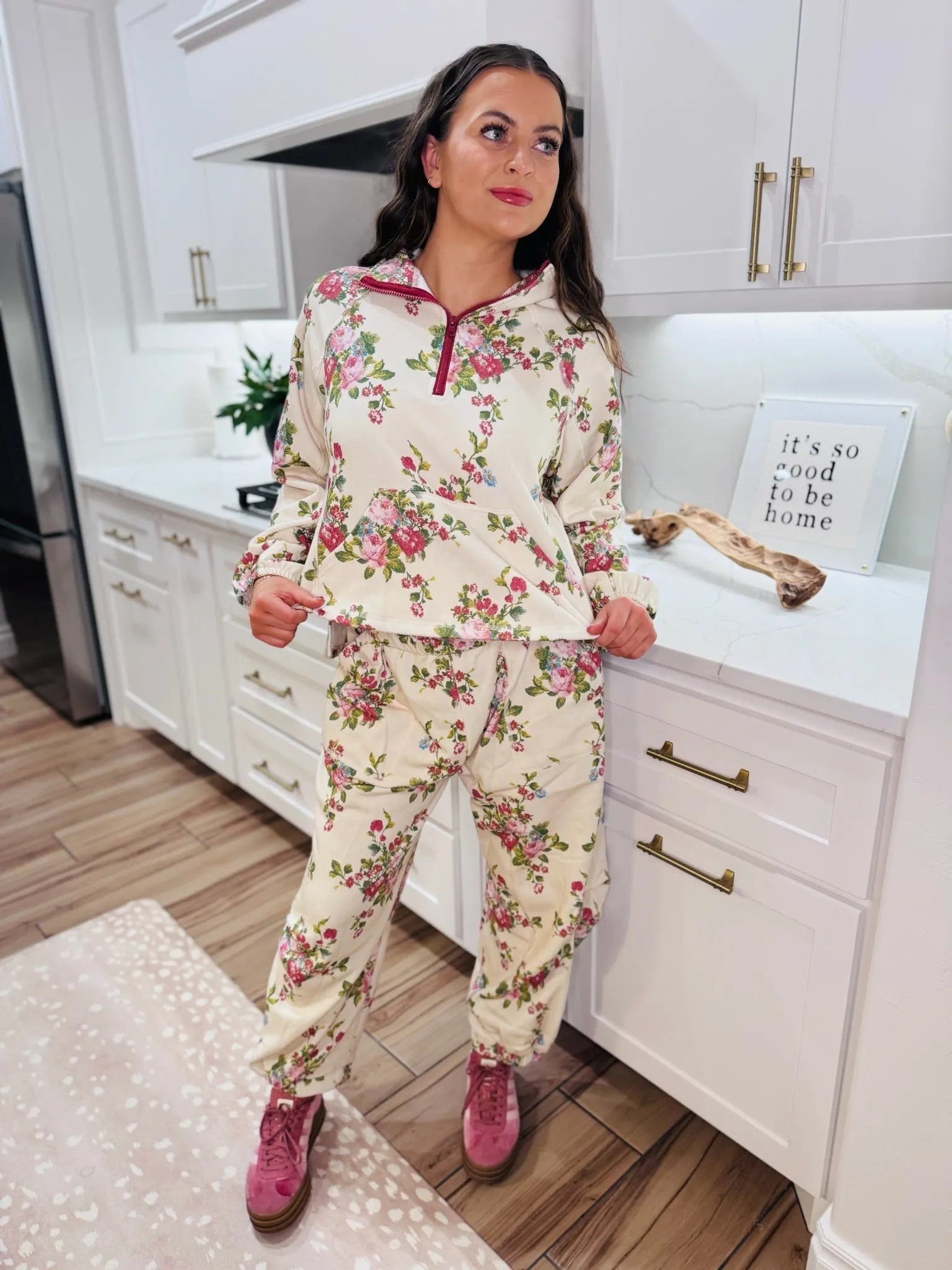 A woman models the Davi & Dani floral half-zip set, featuring a cream base with a pink and green floral print, burgundy