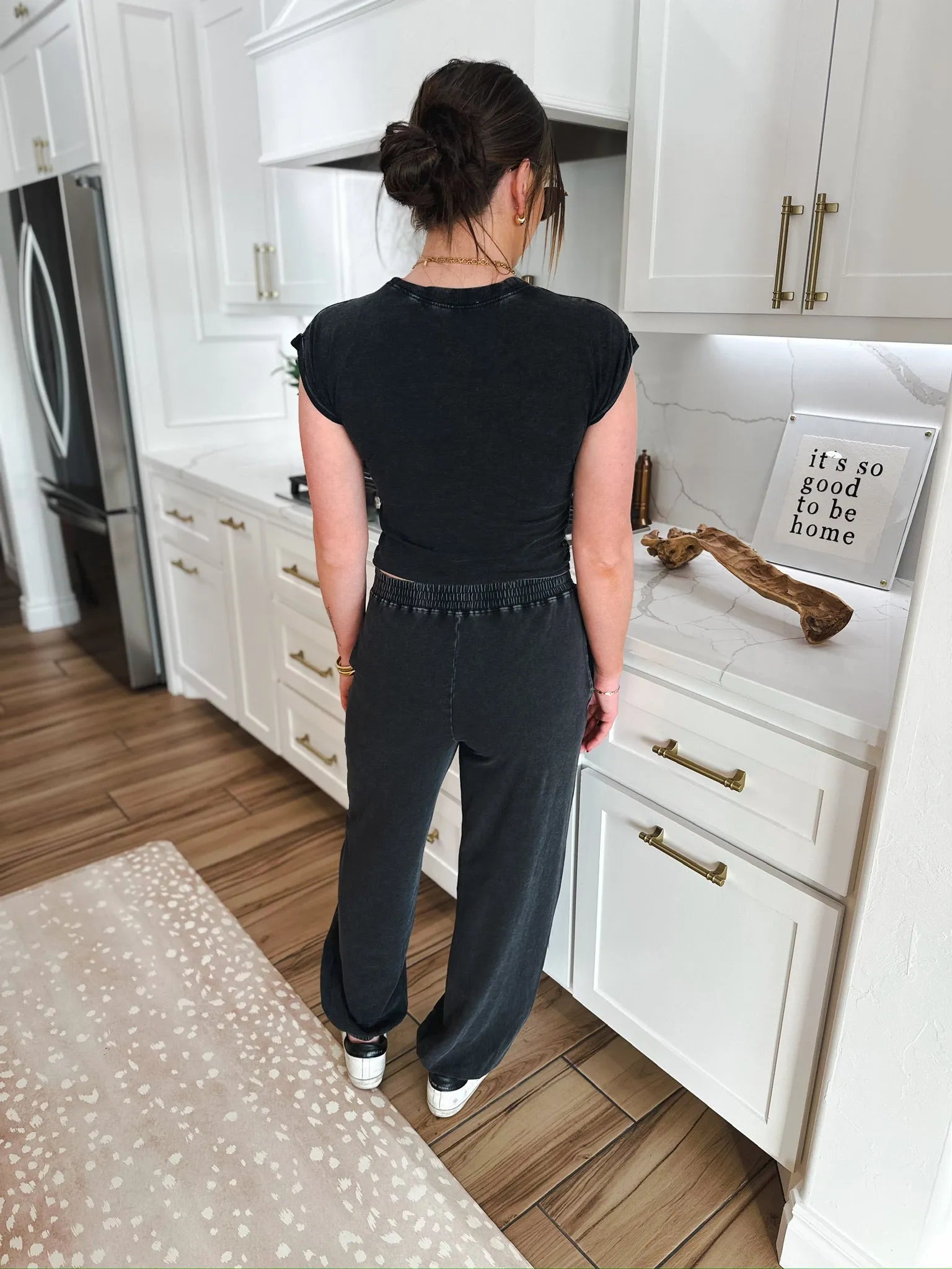 Woman wearing a black mineral washed lounge set with a short-sleeve top and matching wide-leg pants, standing in a modern