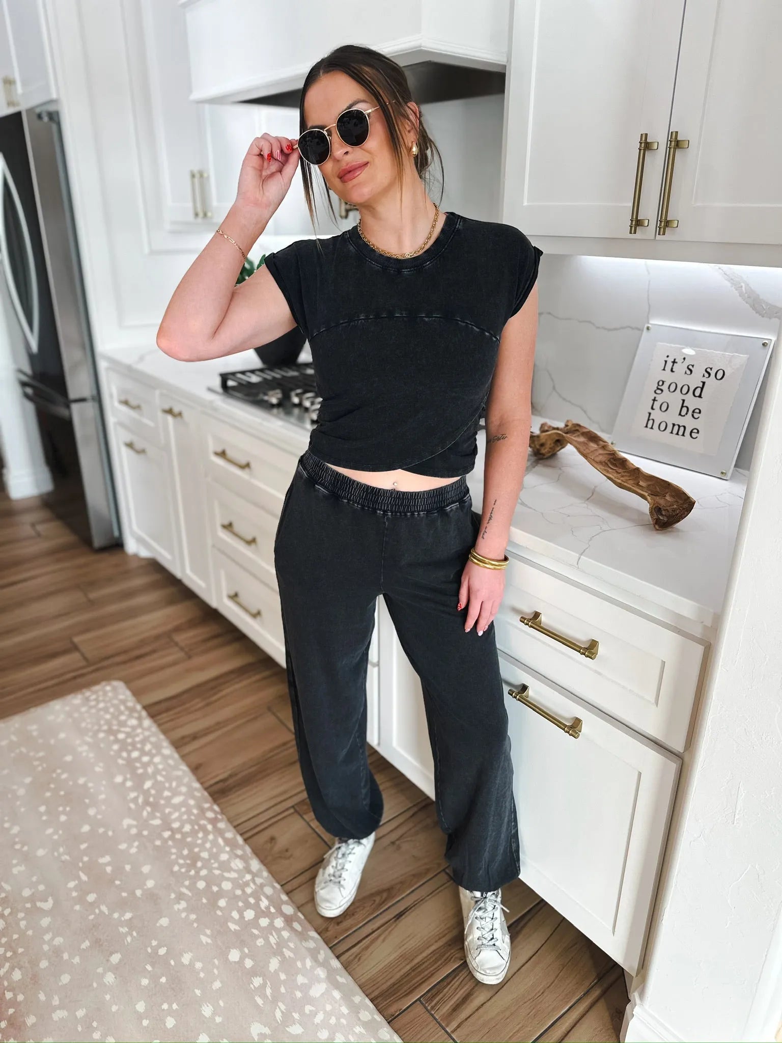 Model wearing a black Double Zero lounge set with a twisted crop top and wide-leg pants, paired with white sneakers and