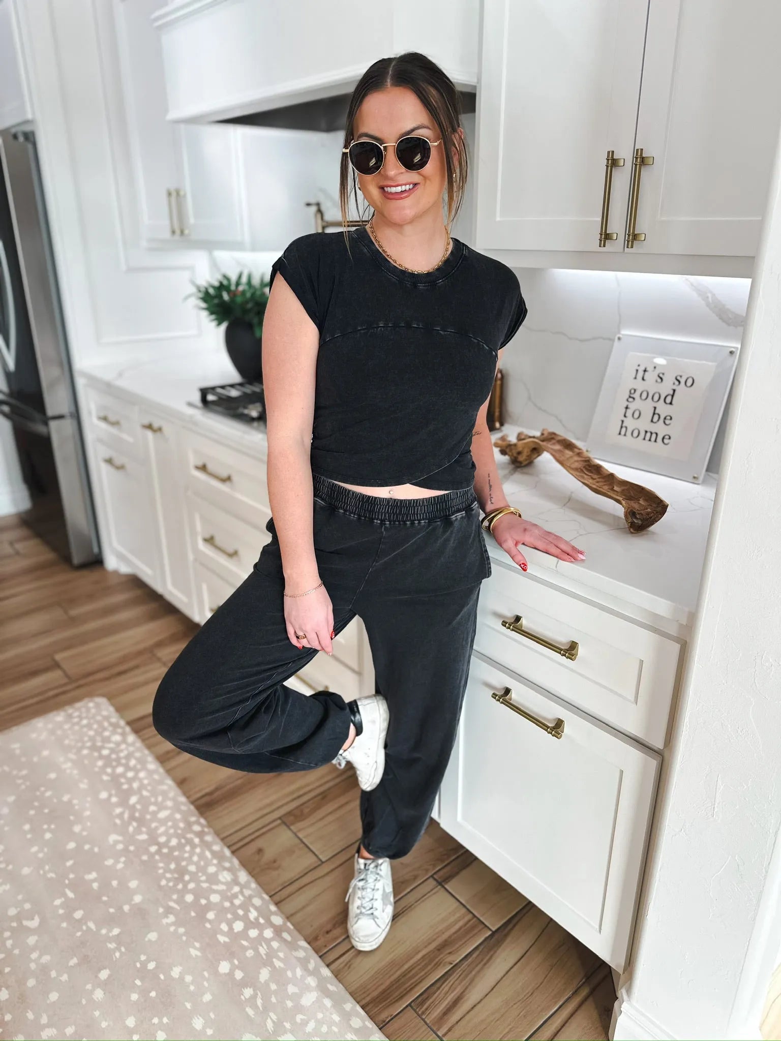 Woman wearing a black washed lounge set, featuring a cropped t-shirt and wide-leg pants. She has sunglasses on and is