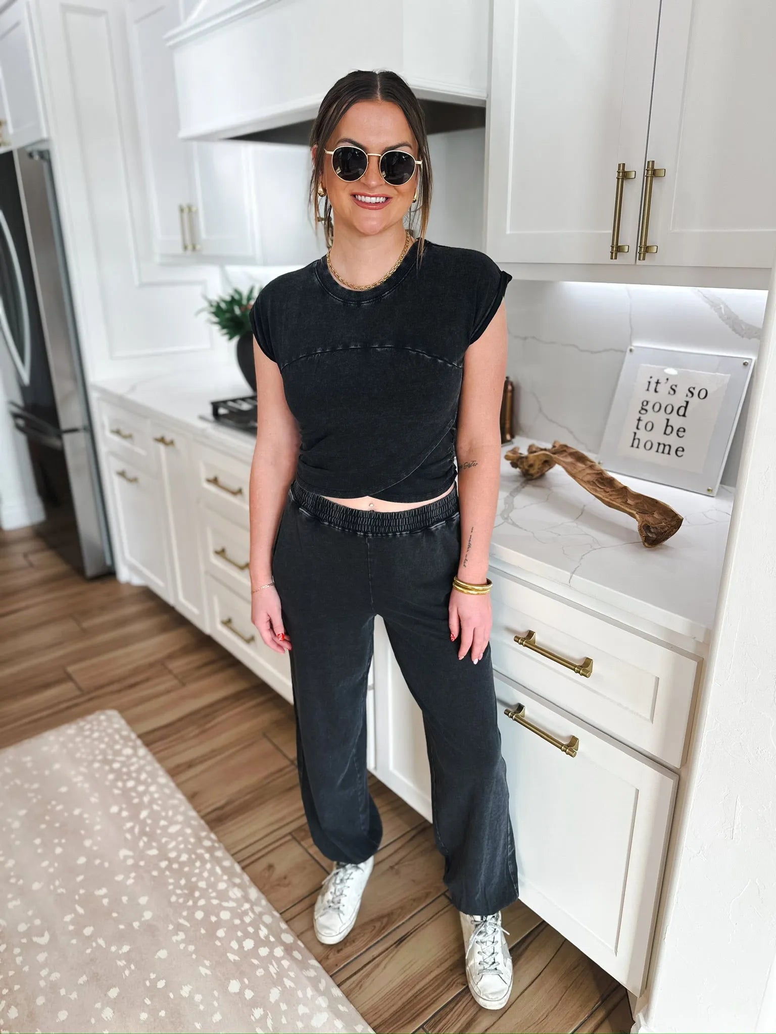 Model wearing a black mineral wash lounge set with a cropped t-shirt and wide-leg pants. She has on round sunglasses and