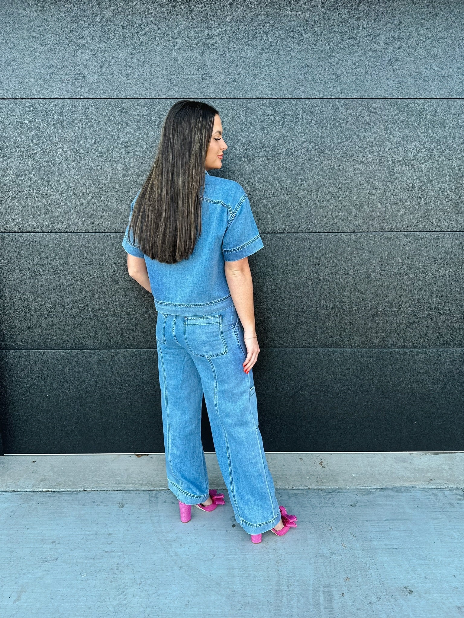 Woman wearing a light wash denim button-down shirt and matching wide-leg cargo pants, styled with pink bow heels.