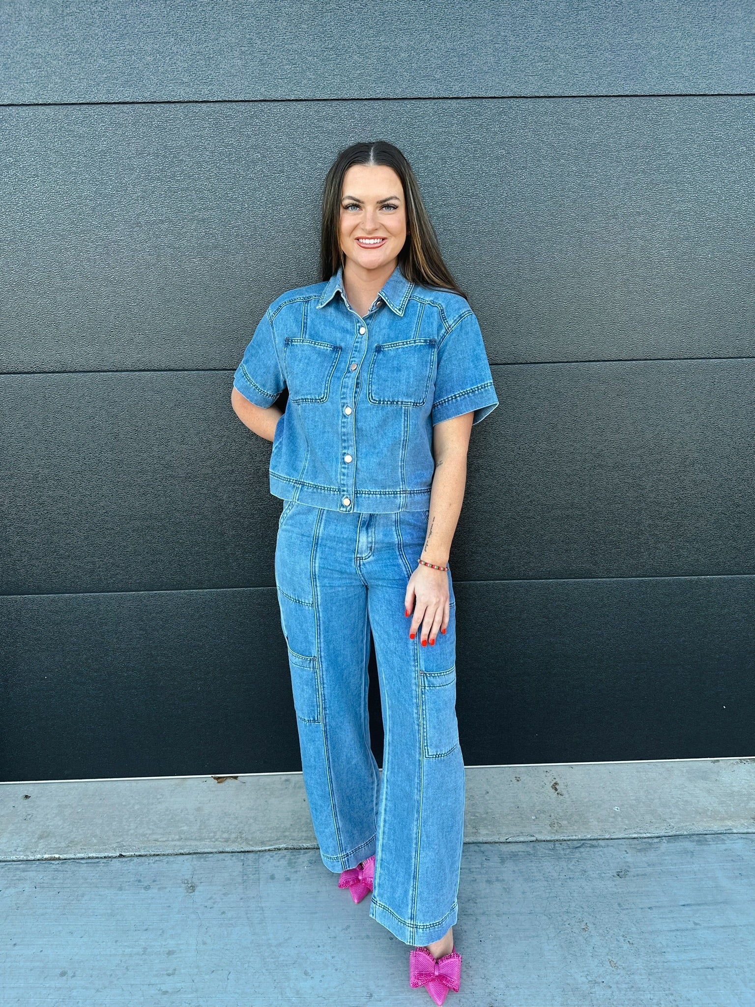 Woman in a light blue denim button-down shirt with short sleeves and two chest pockets, paired with matching light blue