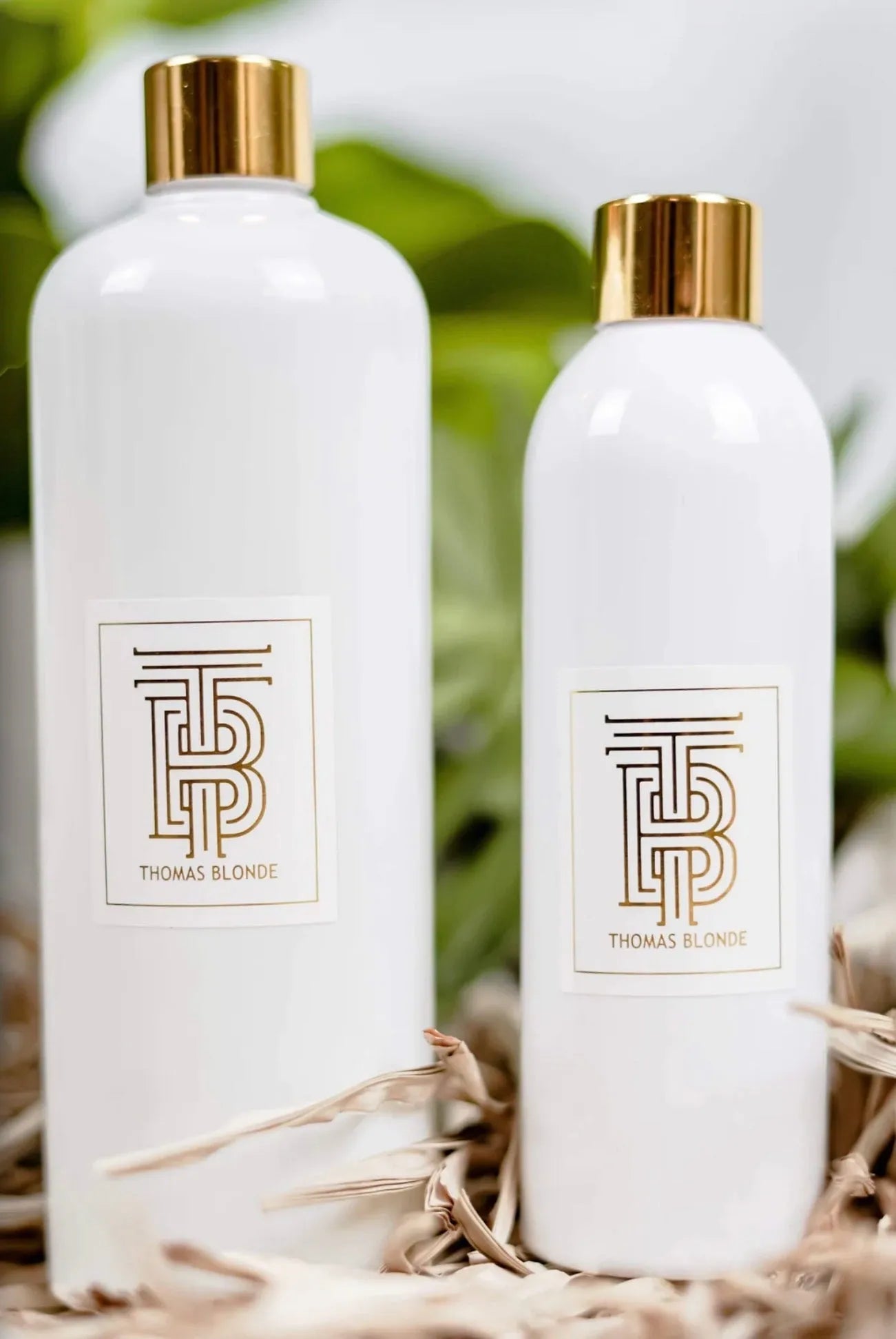 Two white bottles with gold caps and Thomas Blonde logo. One bottle is larger than the other.