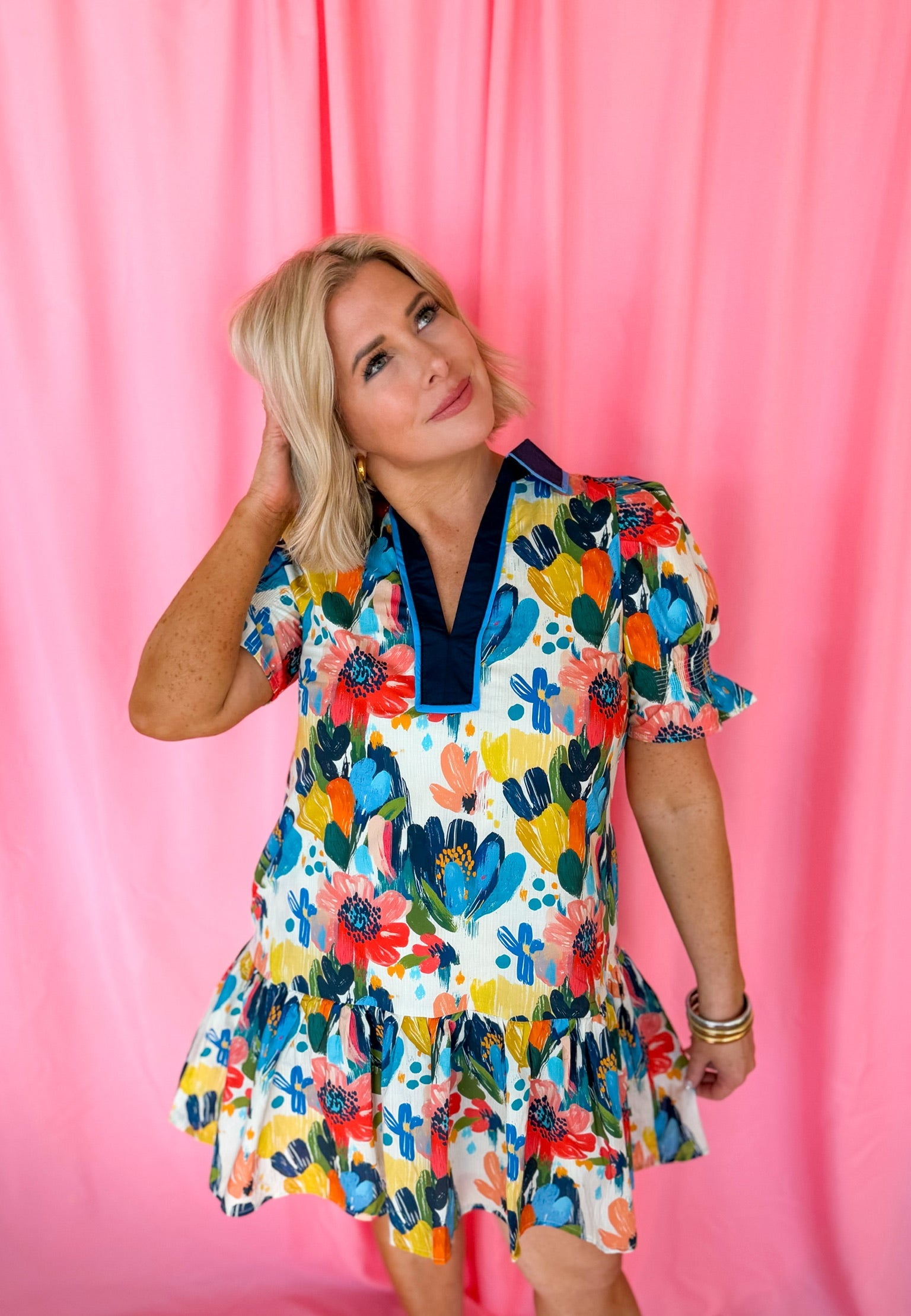 Entro blue spring flower puffer sleeve dress with V-neck and ruffled hem, on a woman with blonde hair against a pink